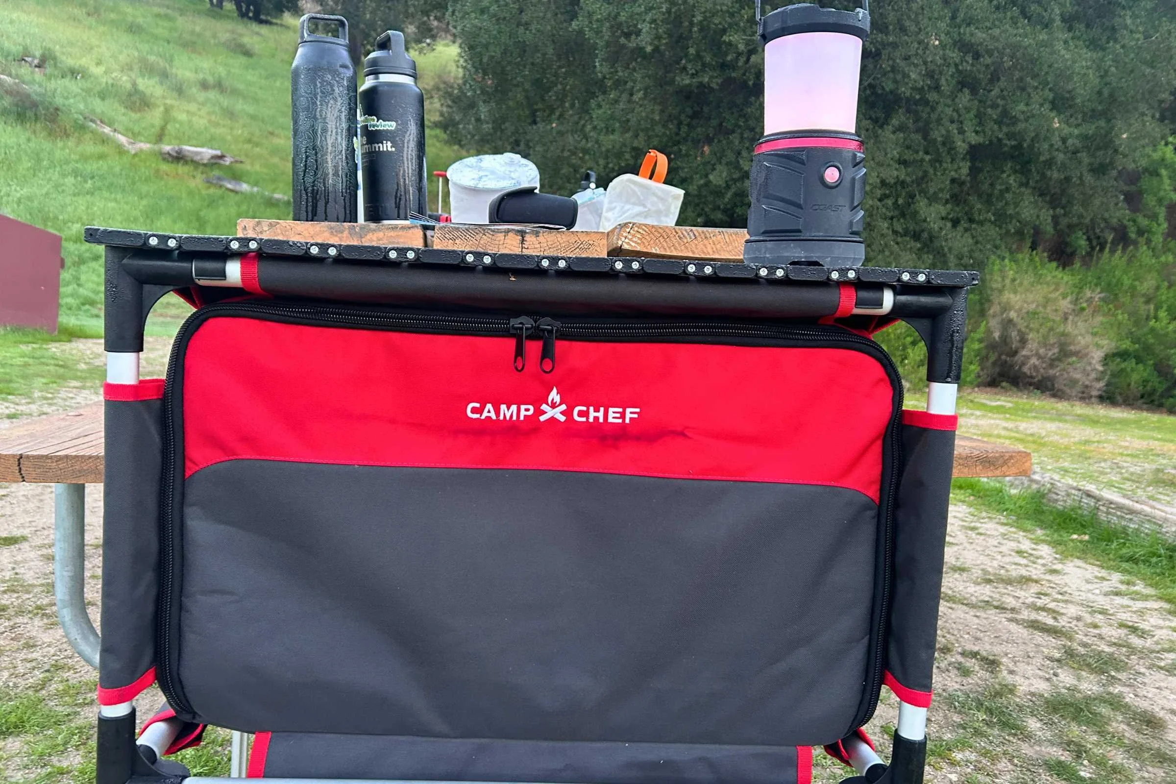   Camp Chef Sherpa Table used as a camp kitchen with cookware and drinks on the tabletop  