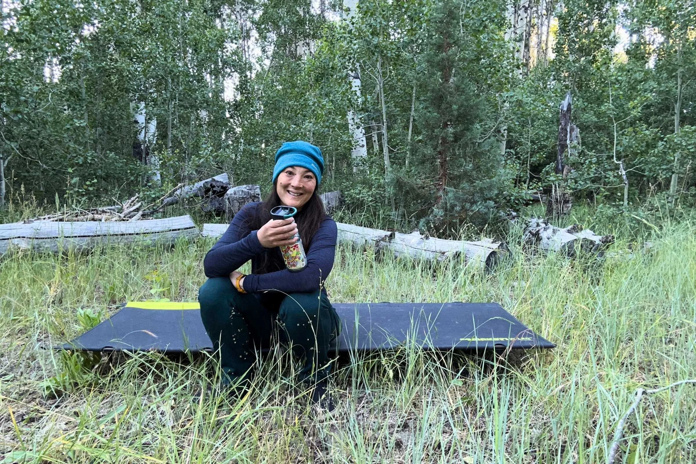  The author Liz Thomas is sitting on the edge of the Zempire W Leg Stretcher V2 camping cot. 