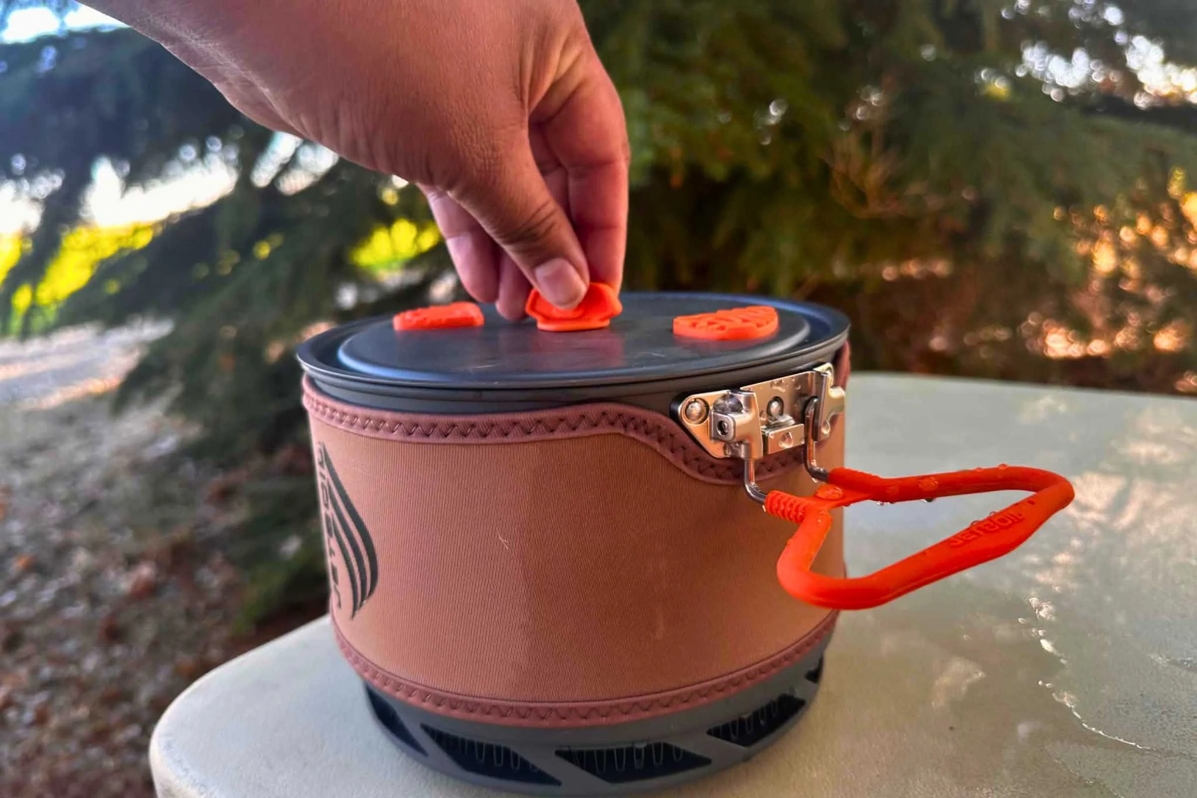   A hand taking the pot lid off using the rubberized handle.  