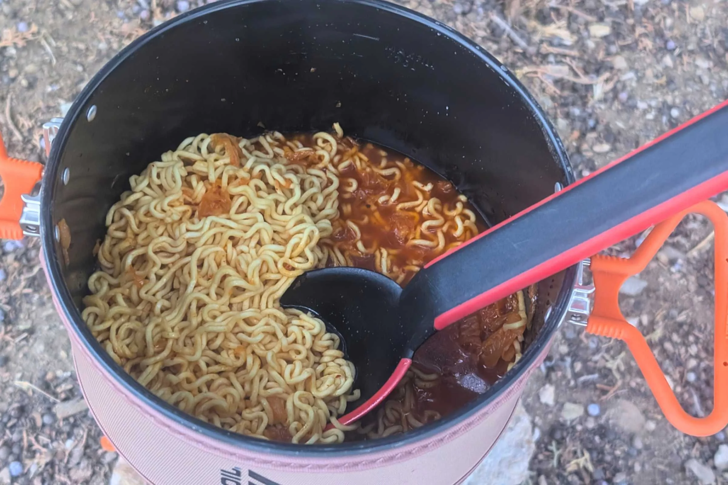   &nbsp;A spoon stirs ramen simmering in the pot.  