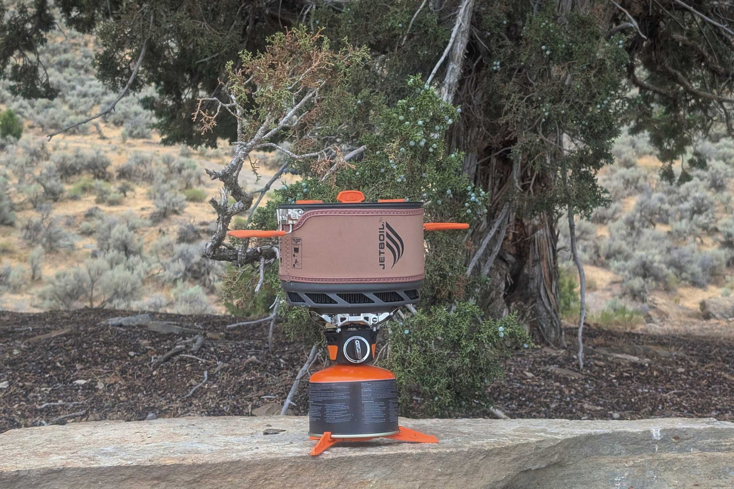   The stove is set up on a rock with the pot on top at a far distance.  