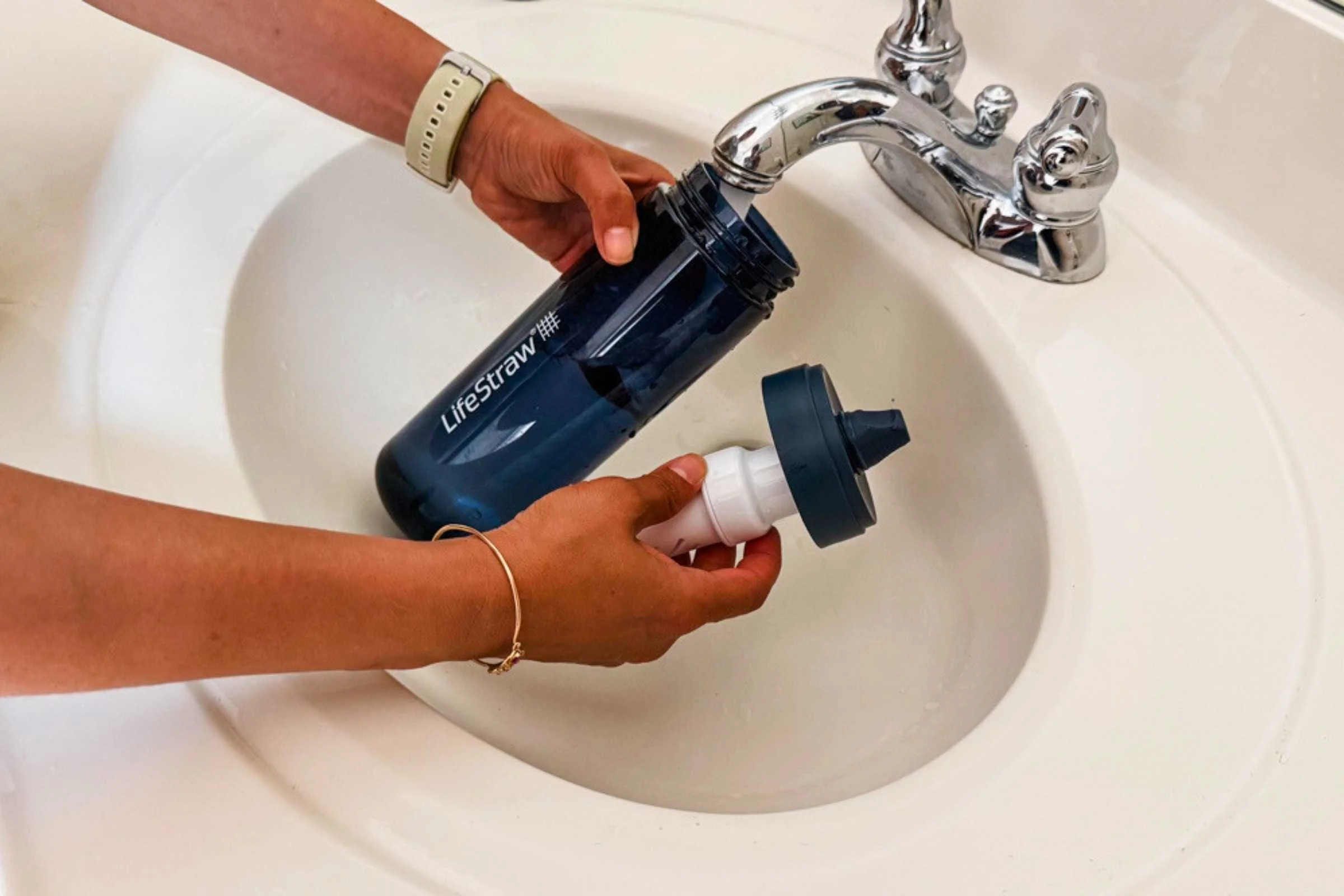   A filter water bottle being filled at a tap, with the filter element visible through the transparent body.   Photo courtesy Karthika Gupta  
