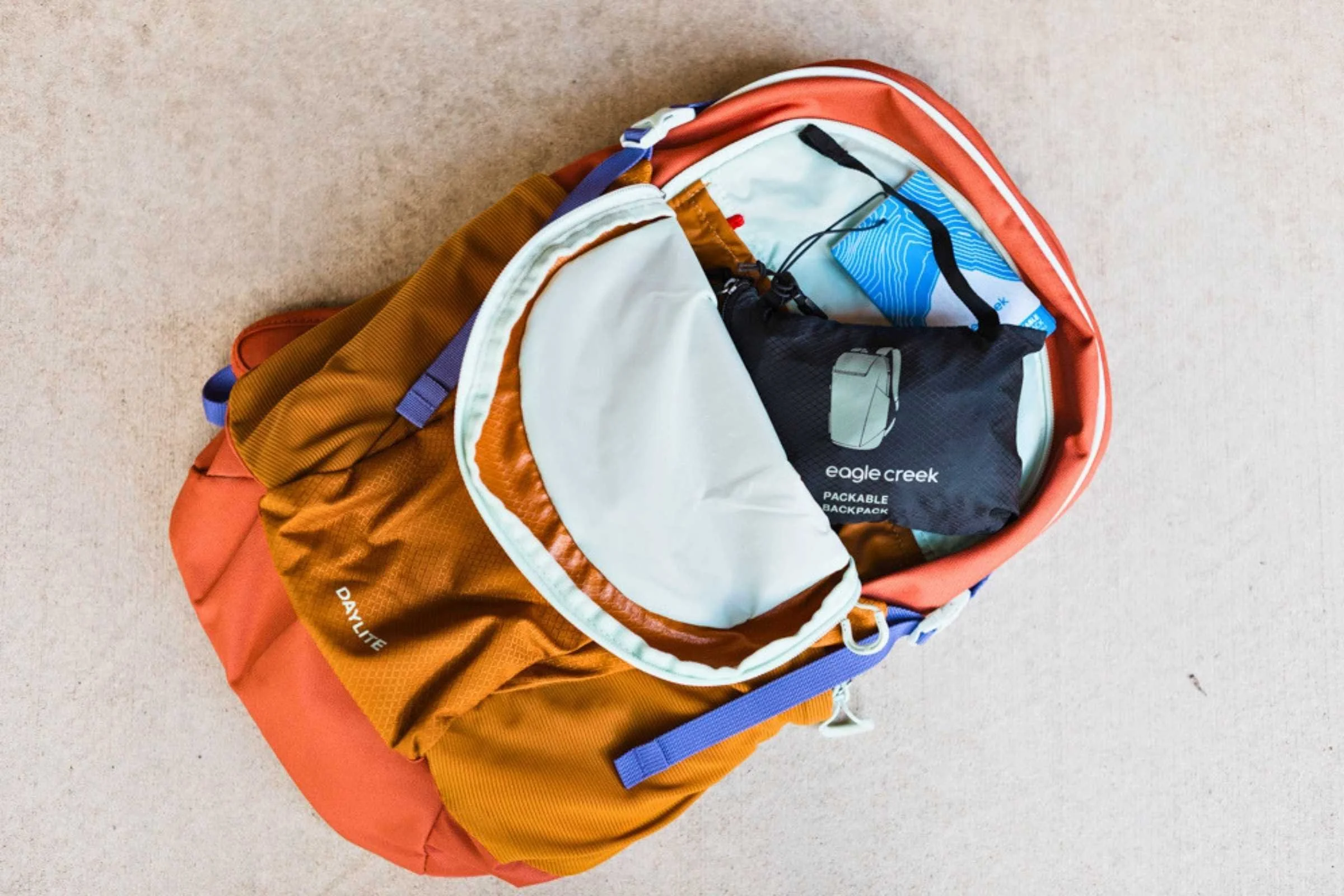   The Osprey Daylite shown packed with travel essentials, highlighting its organized compartments and compact profile for travel.  