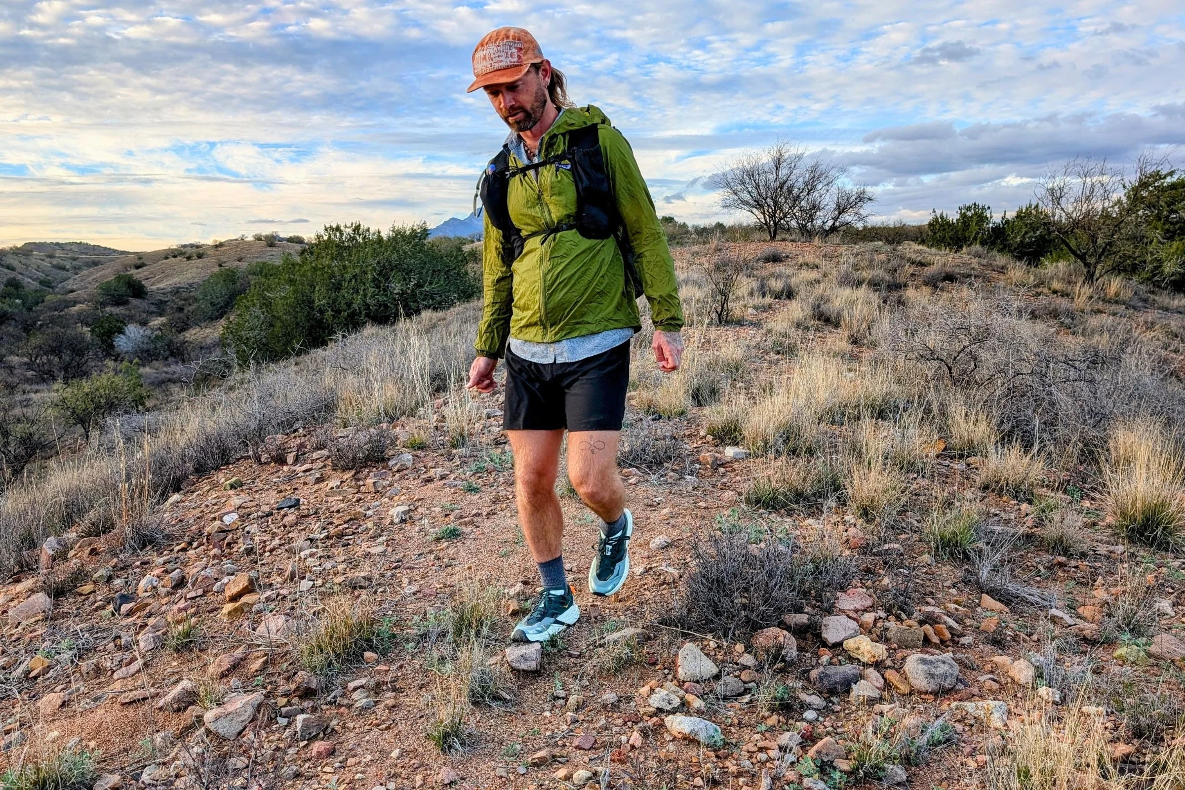   A hiker wearing the Pa’lante V2 with Joey Straps fastpacks through rocky terrain, showing the pack in use on the trail.  