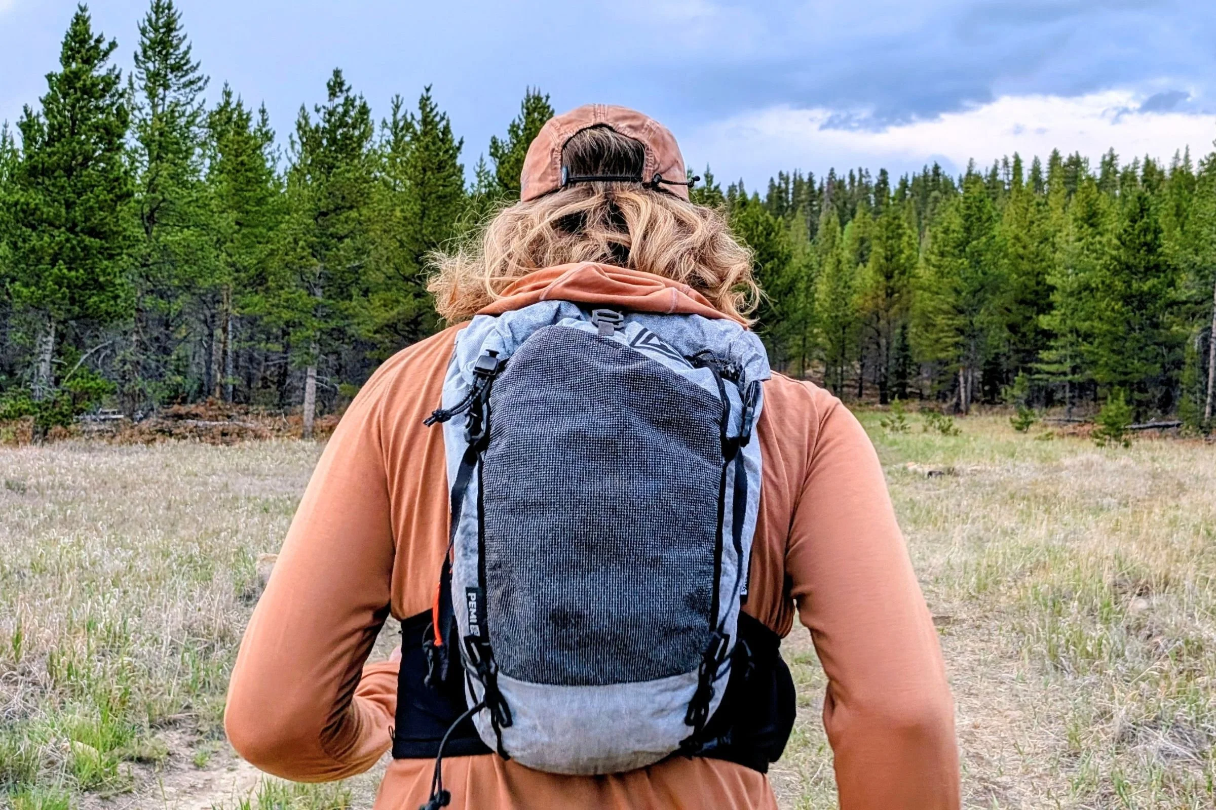   The Hyperlite Mountain Gear Pemi 15 sits close against a hiker’s back on the trail, highlighting its compact profile and stable fit.  