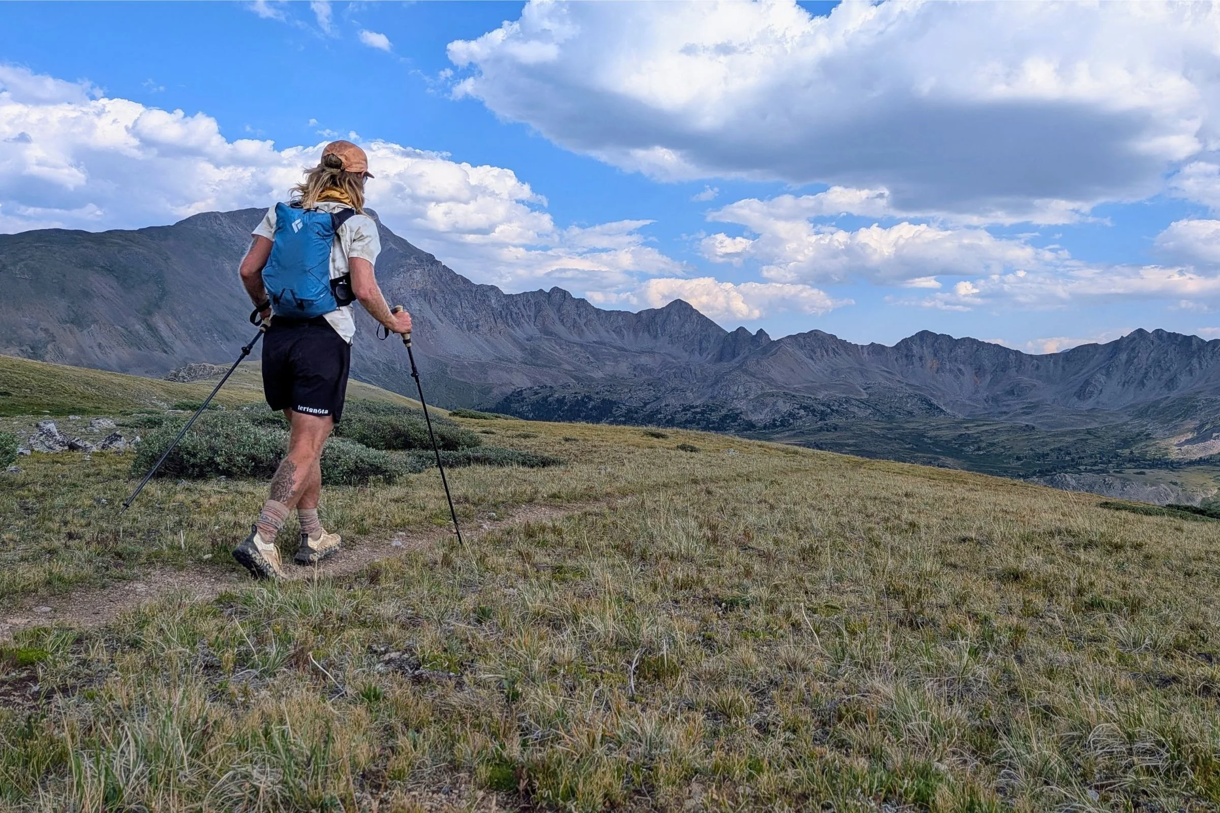   A tester wearing the Black Diamond Distance 15 while moving across an open mountain trail.  