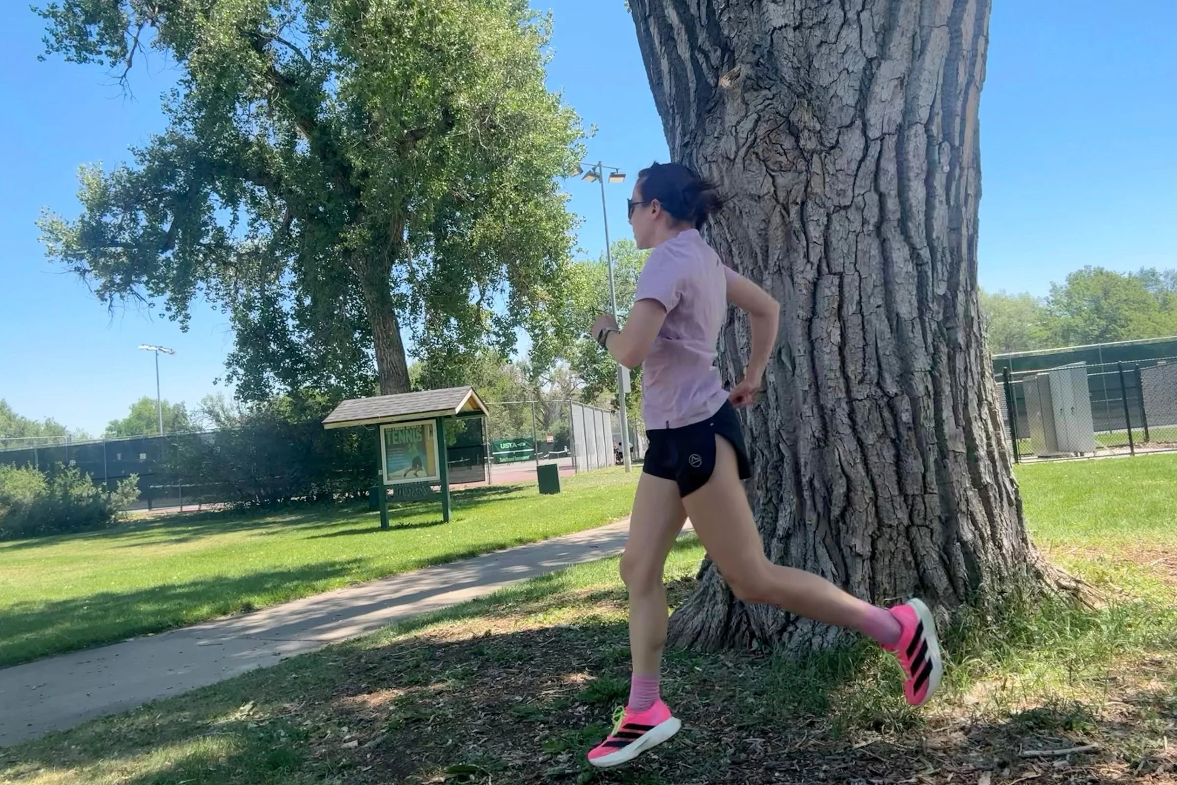   A runner wearing the Patagonia Capilene Cool Ultra shirt while running past a large tree.  