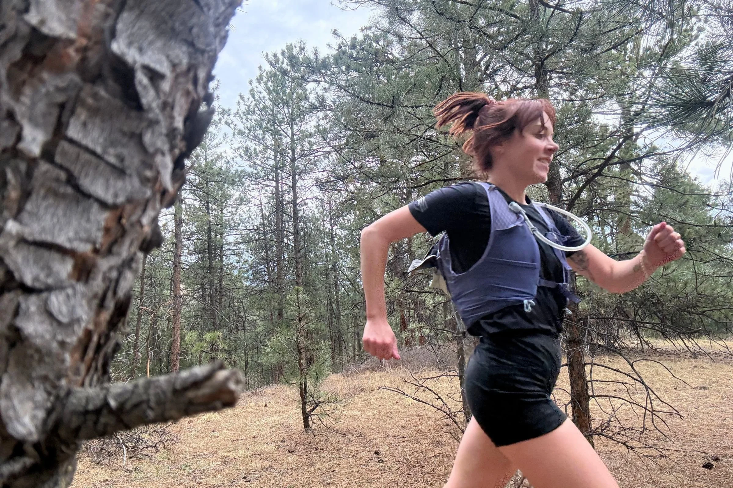   A runner wearing the Janji Run All Day Tee on a wooded trail.  