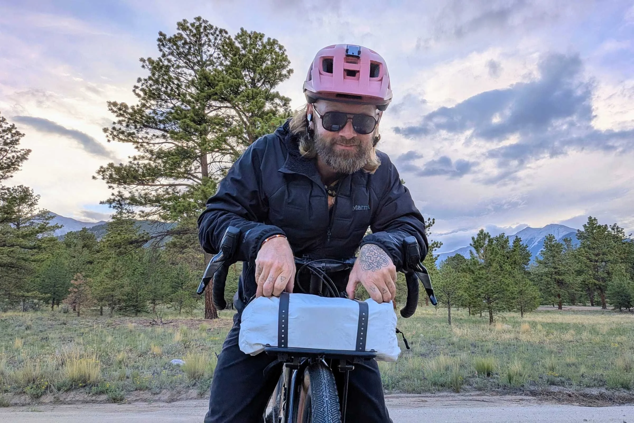   A rider uses the Portland Design Works OxRack Front Rack to carry gear on the front of the bike, highlighting the rack’s broad platform and secure setup.  