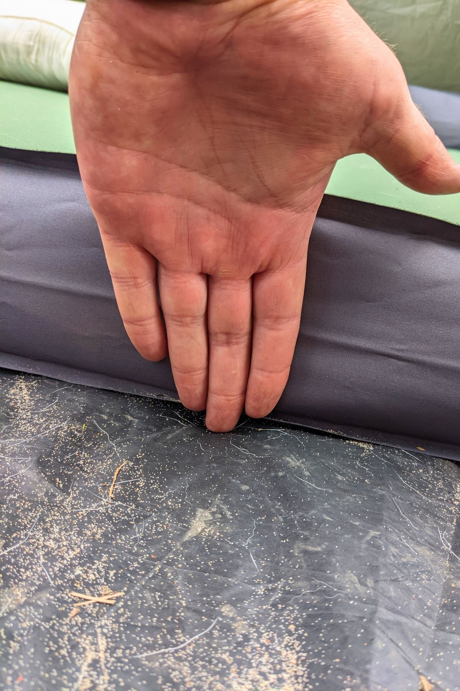   A hand measures the nearly 4-inch thickness of the EXPED MegaMat, showing the substantial cushioning that makes it feel more like a bed than a traditional camping pad.  