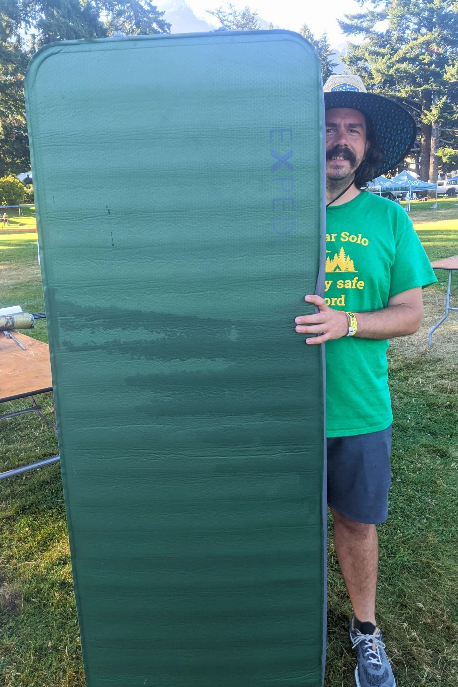   A tester holds the fully inflated EXPED MegaMat upright, demonstrating its large dimensions and substantial sleeping surface.  