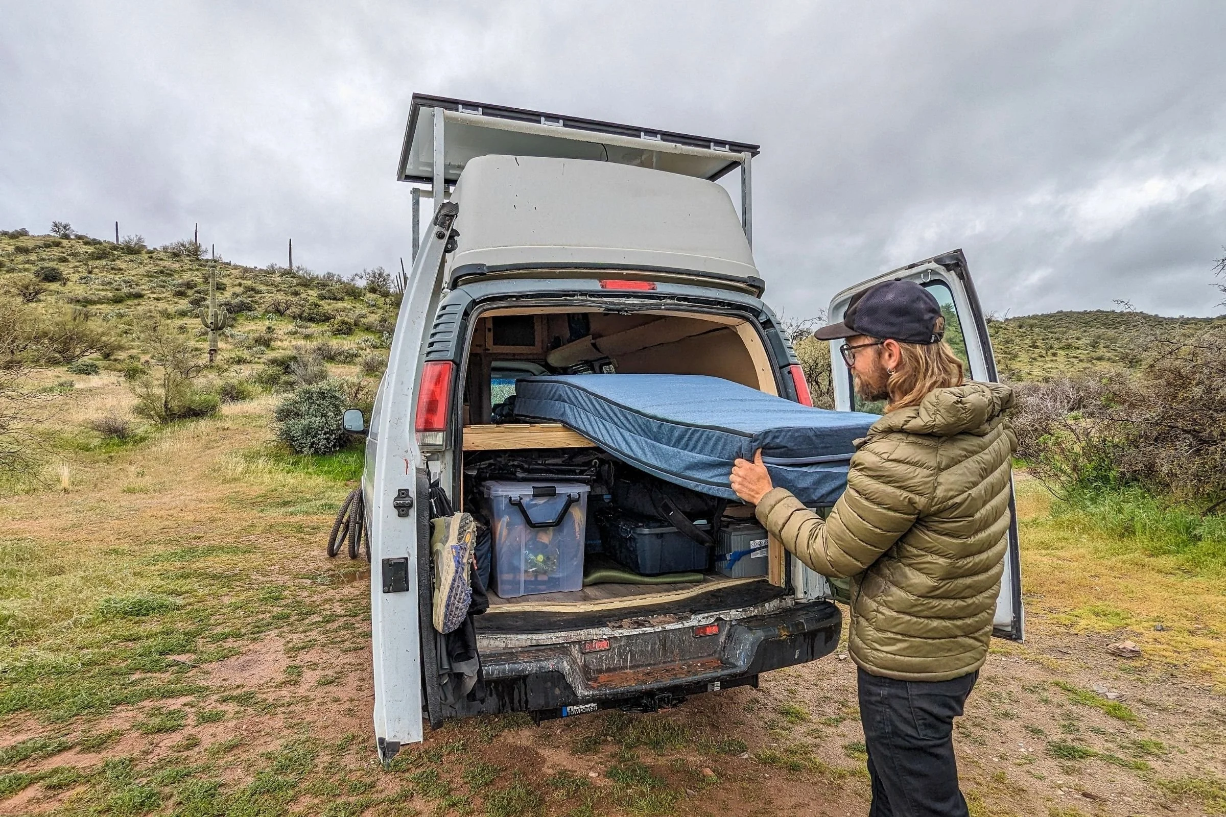   The HEST Dually is pulled from the back of a camper van, highlighting its foldable design and suitability for van camping.  
