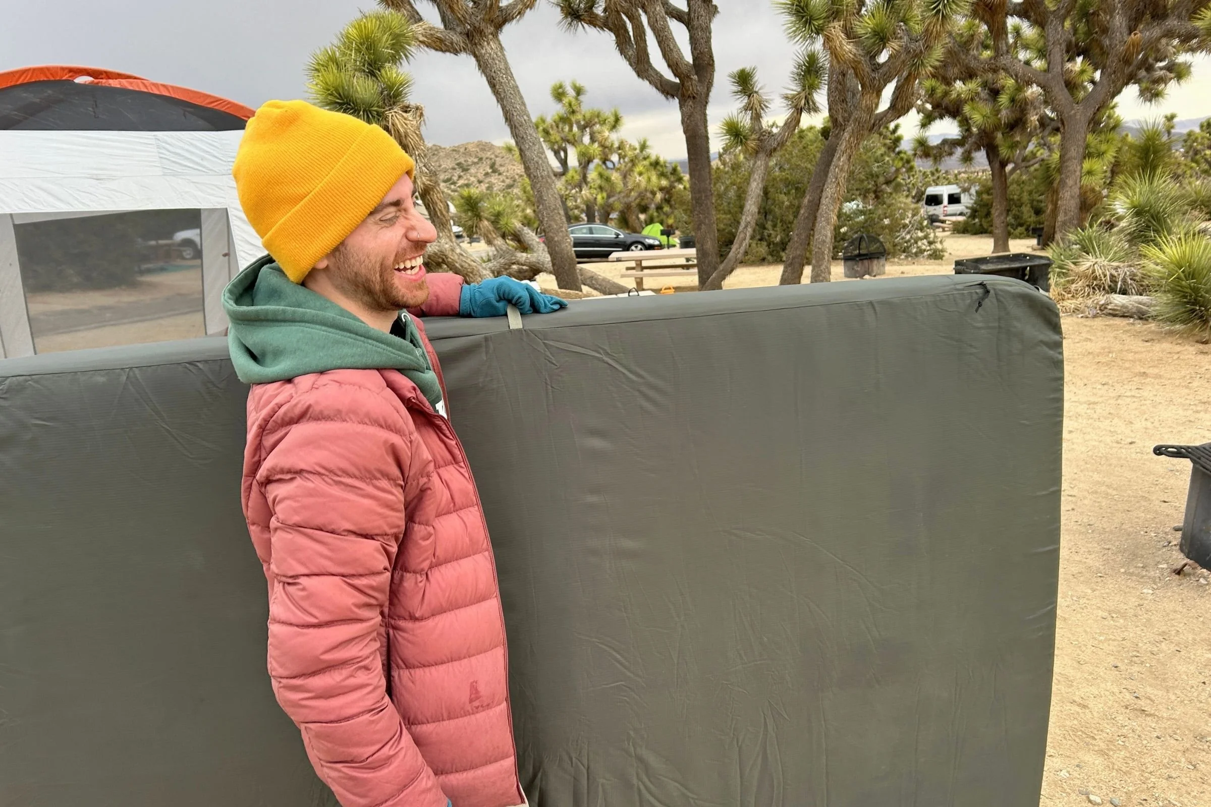   Man carryin the EXPED MegaMat Duo at a campsite.  