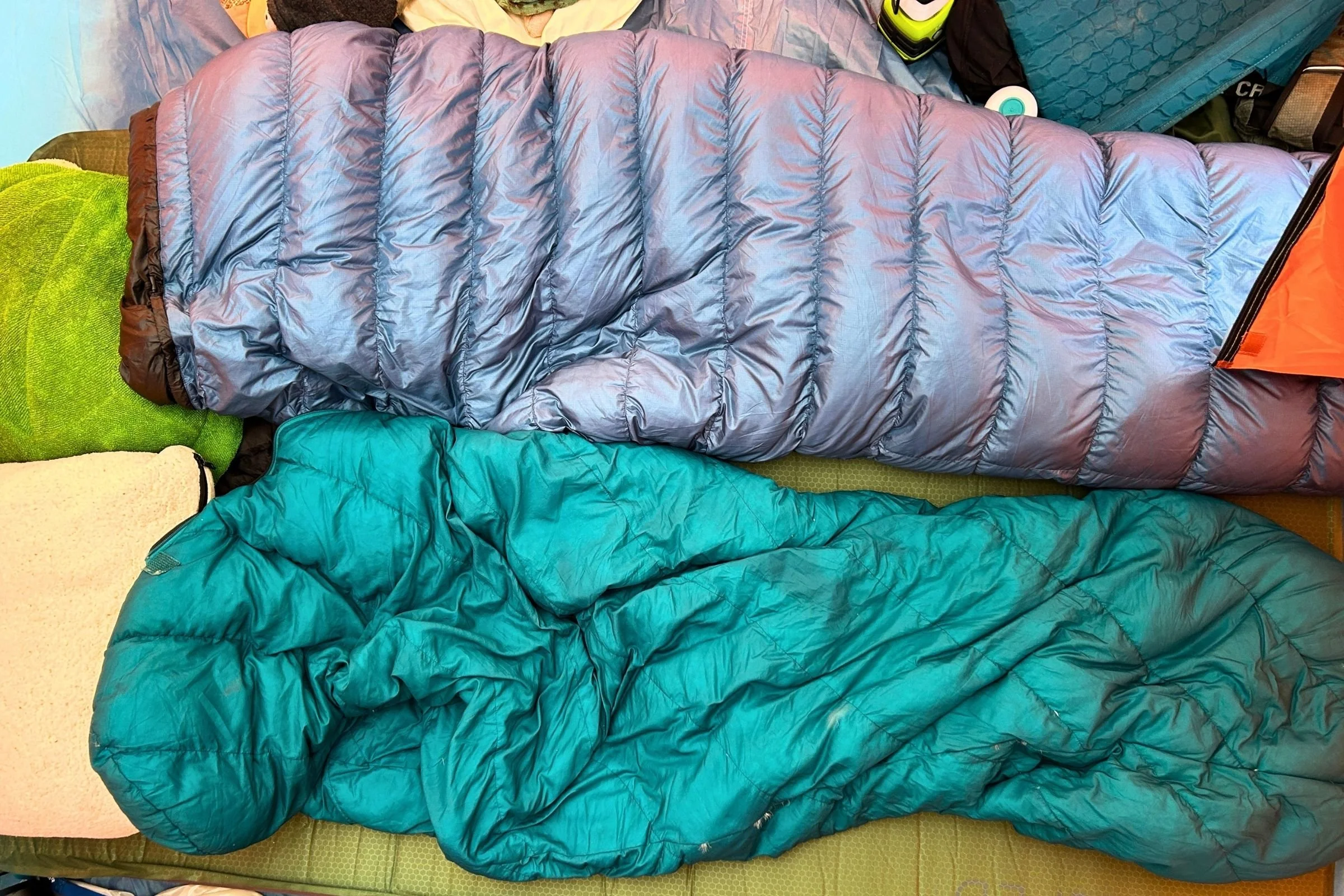   The EXPED MegaMat Duo is shown alongside sleeping bags, highlighting its generous size and suitability for comfortable two-person camping.  
