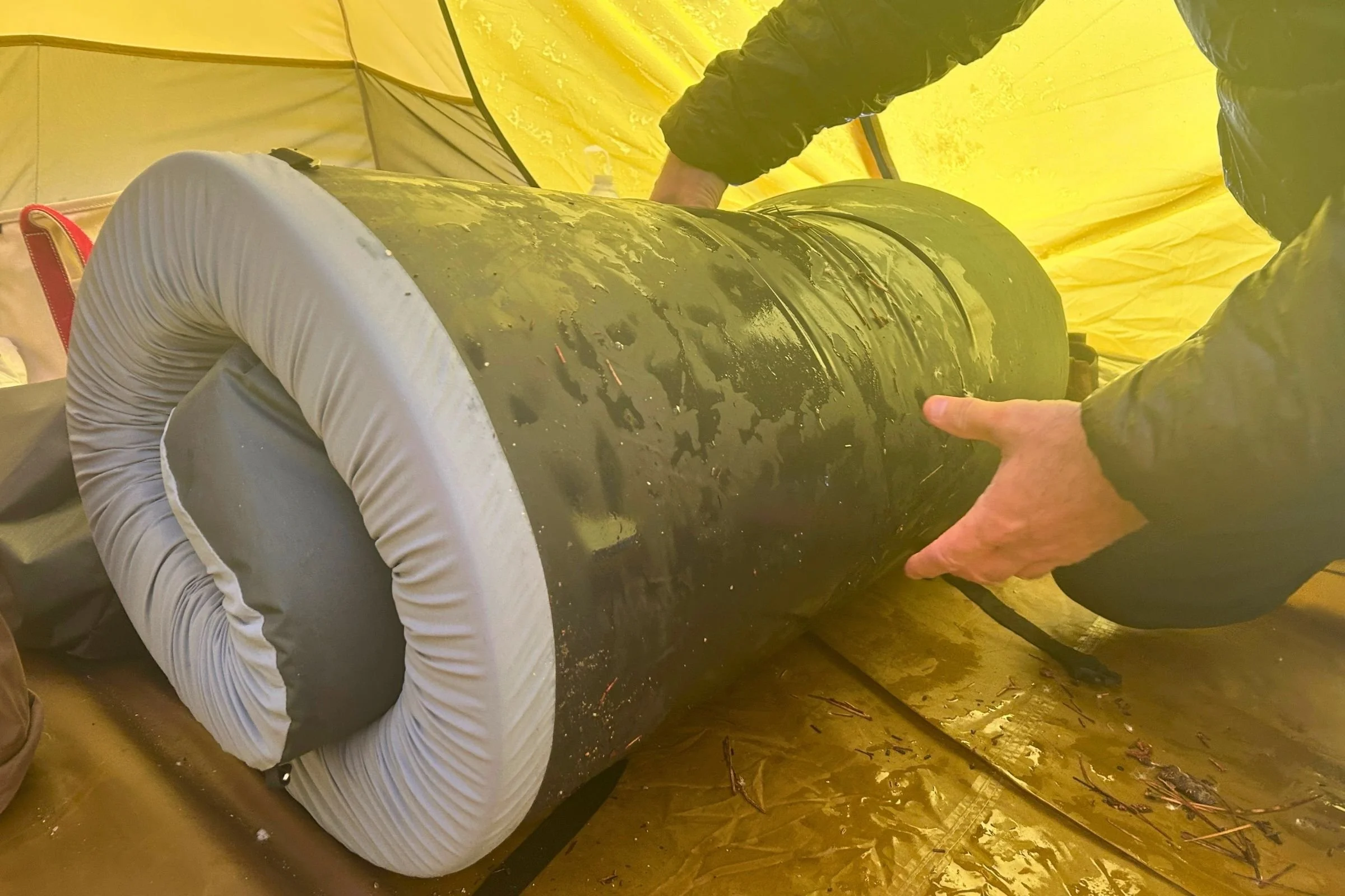   The HEST Sleep System Sleeping Pad is shown rolled up inside a tent, highlighting its substantial foam construction and packed size.  