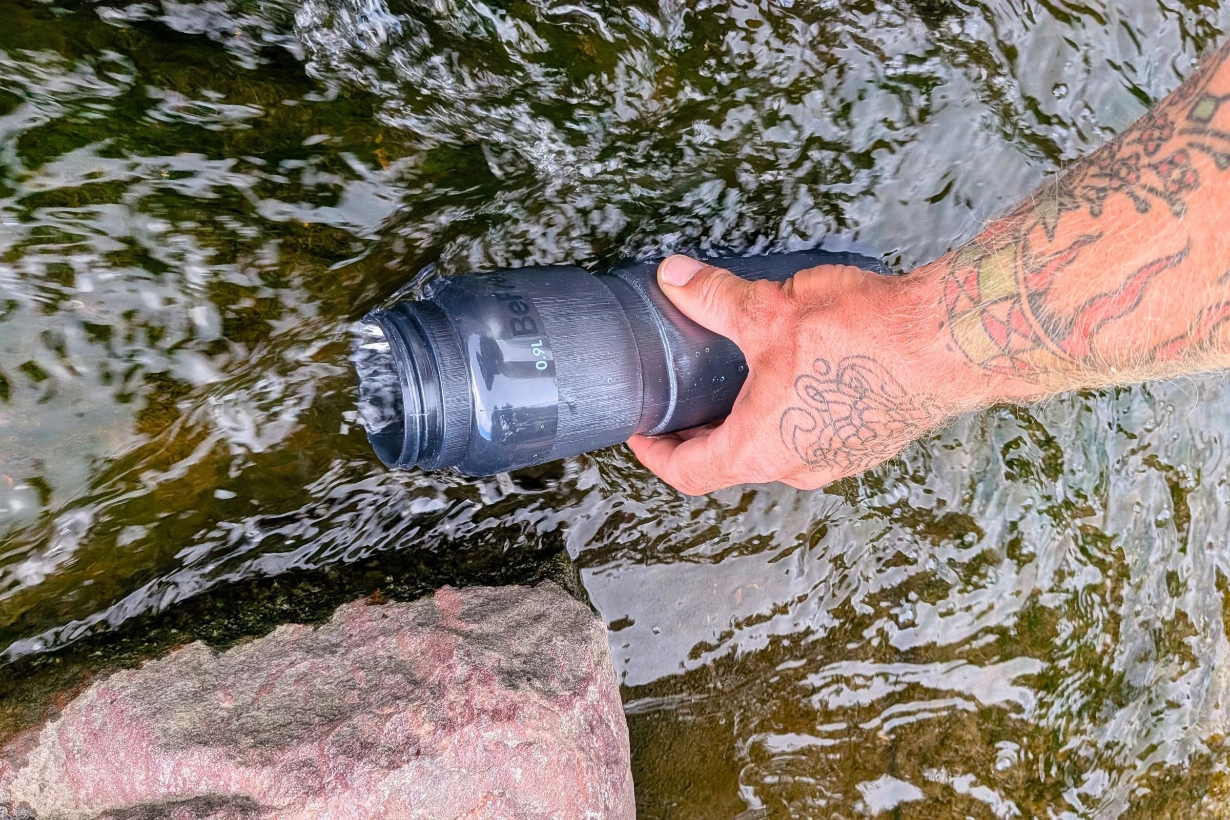   The Katadyn BeFree AC Bottle is filled directly from a stream, showing how its integrated filter makes it practical for refilling from natural water sources.  