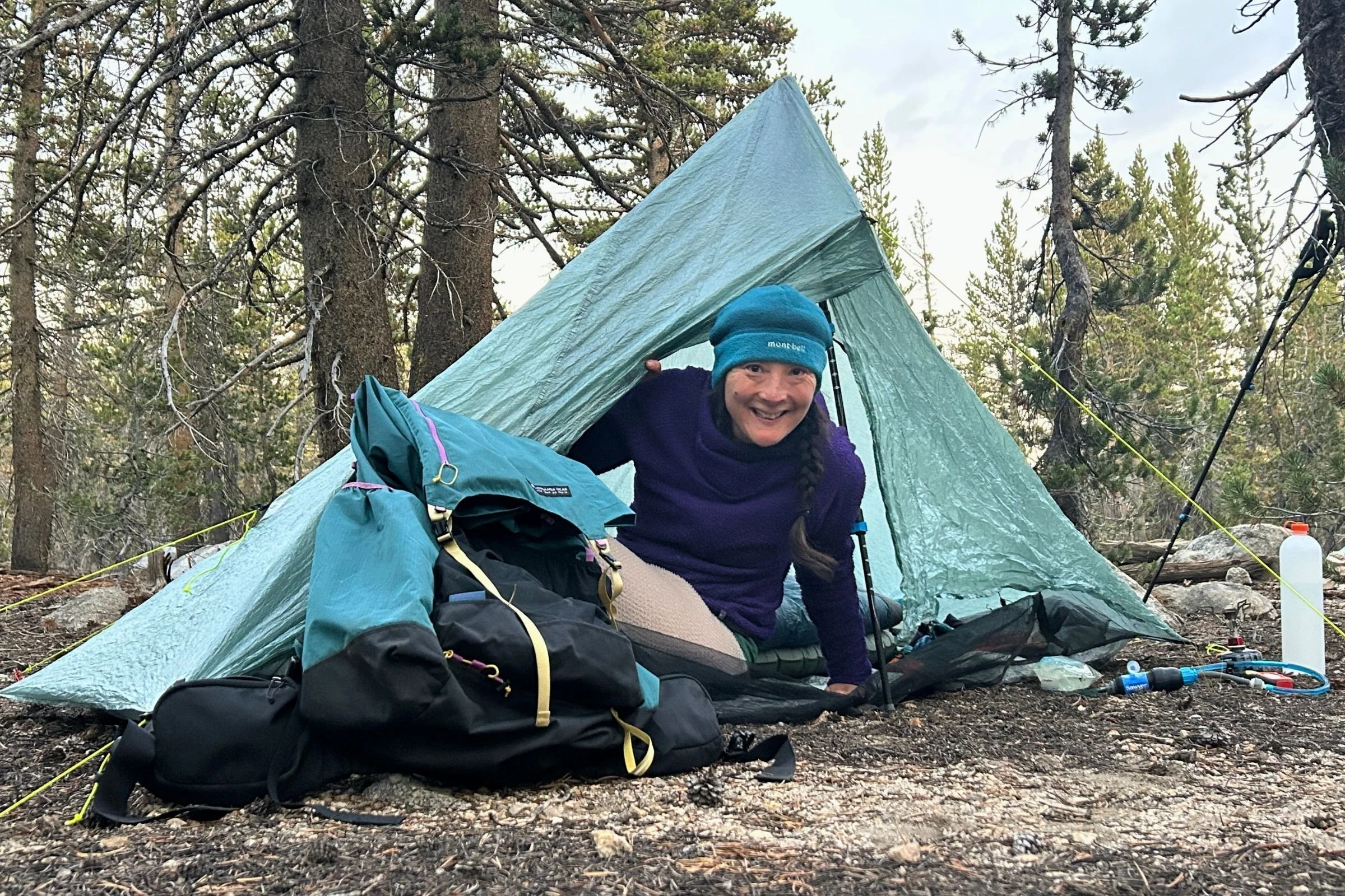   The Gossamer Gear Mariposa 60 sits beside a backpacker at camp, showing how its spacious design accommodates a full backpacking load while remaining lightweight.  