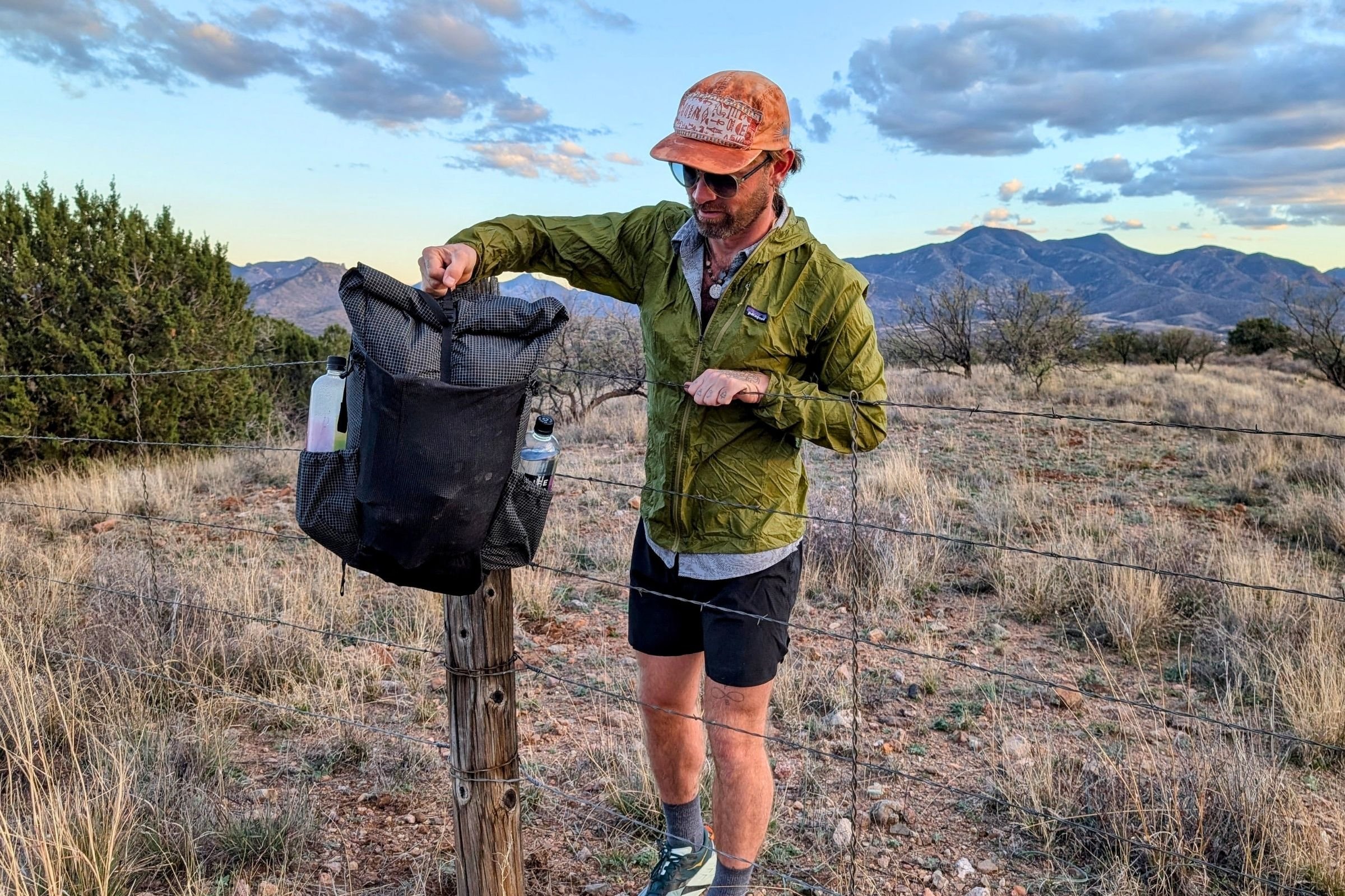   A backpacker packs the Pa’lante V2 with Joey Straps in the field, showing the pack’s roll-top design and flexible capacity.  