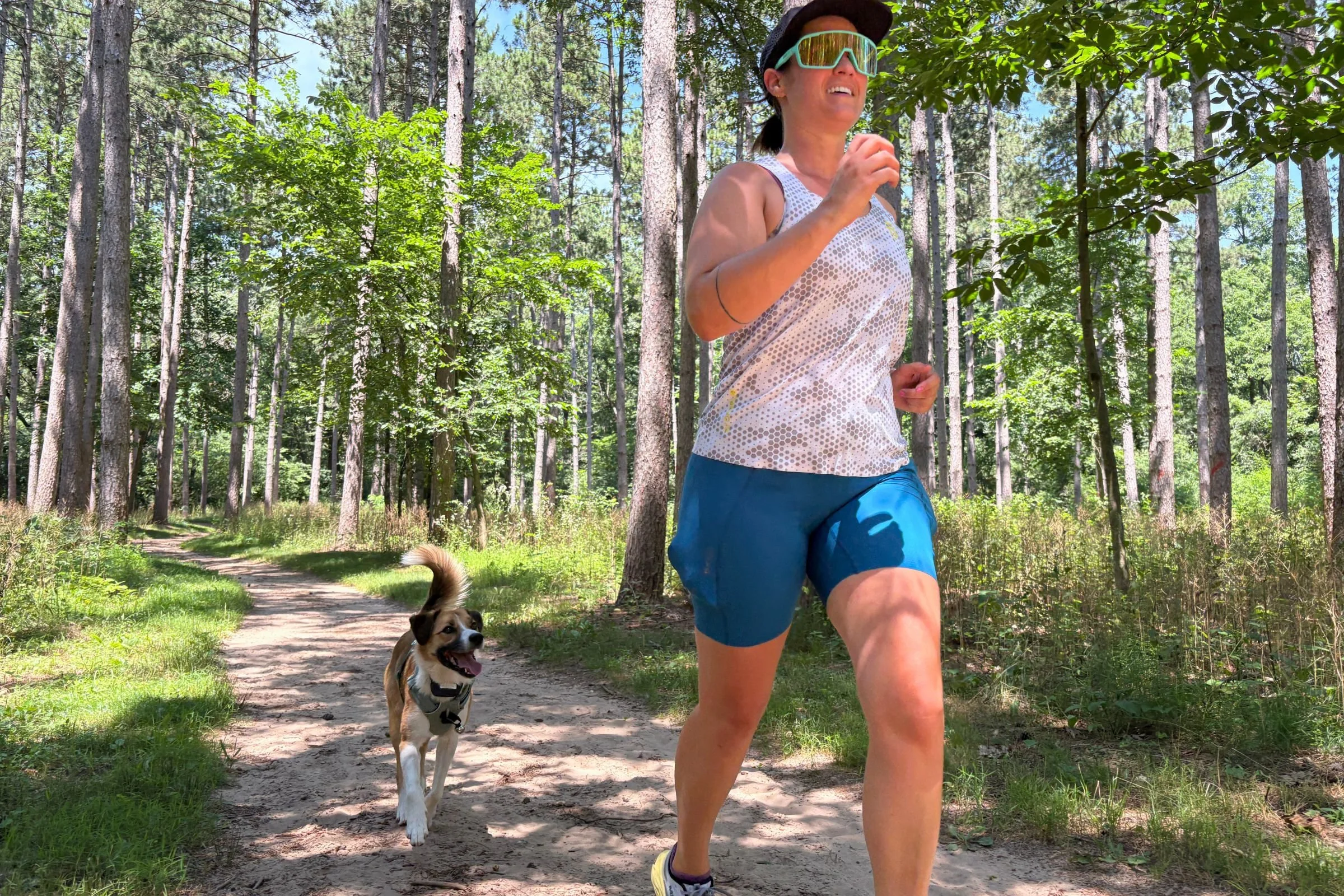   A runner takes her dog along a wooded trail in the Janji Pace Shorts, whose longer inseam helps prevent thigh chafing during longer runs.  