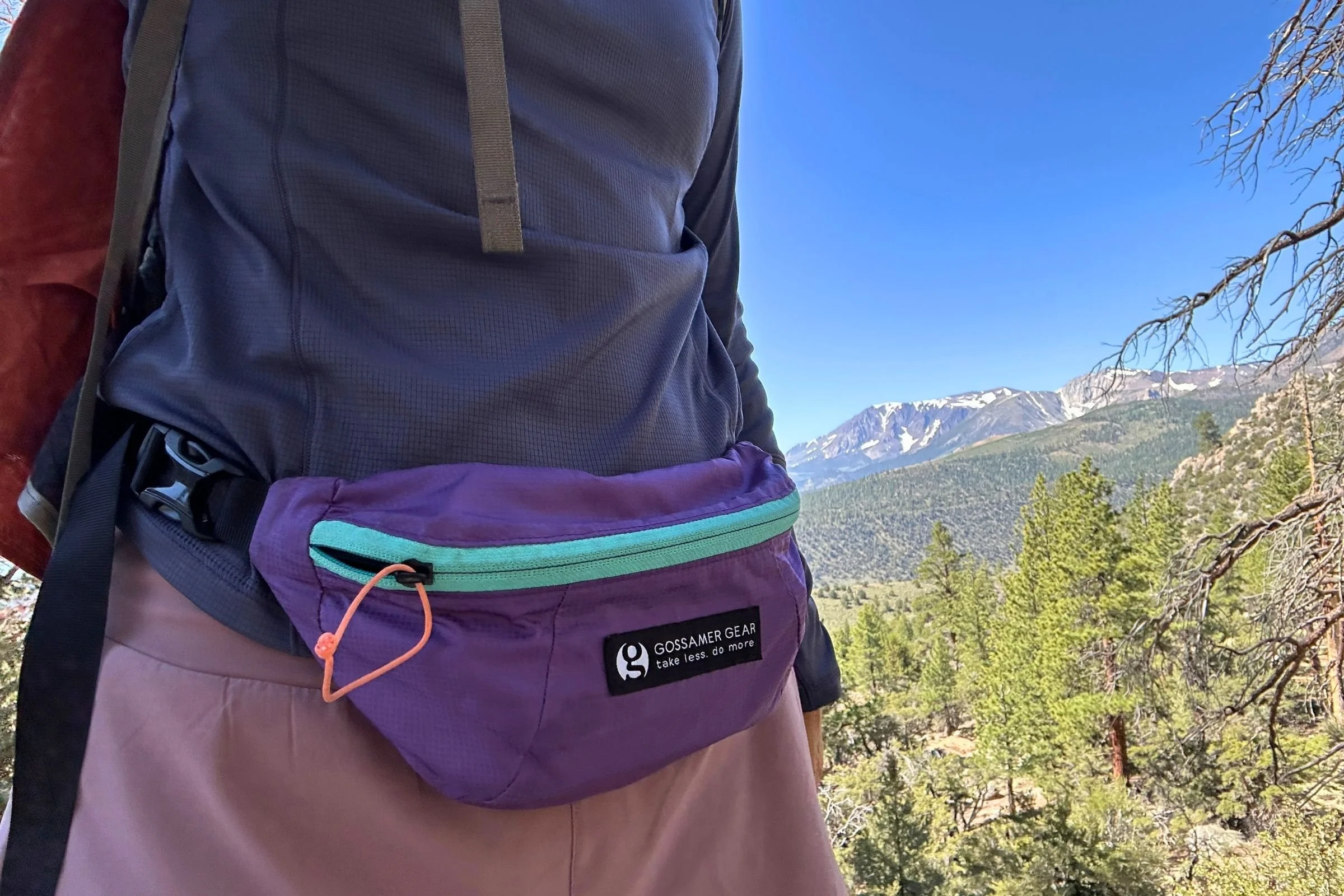   A hiker wears the Gossamer Gear Bumster on the trail, showing the lightweight fanny pack’s compact 1.5-liter design.  