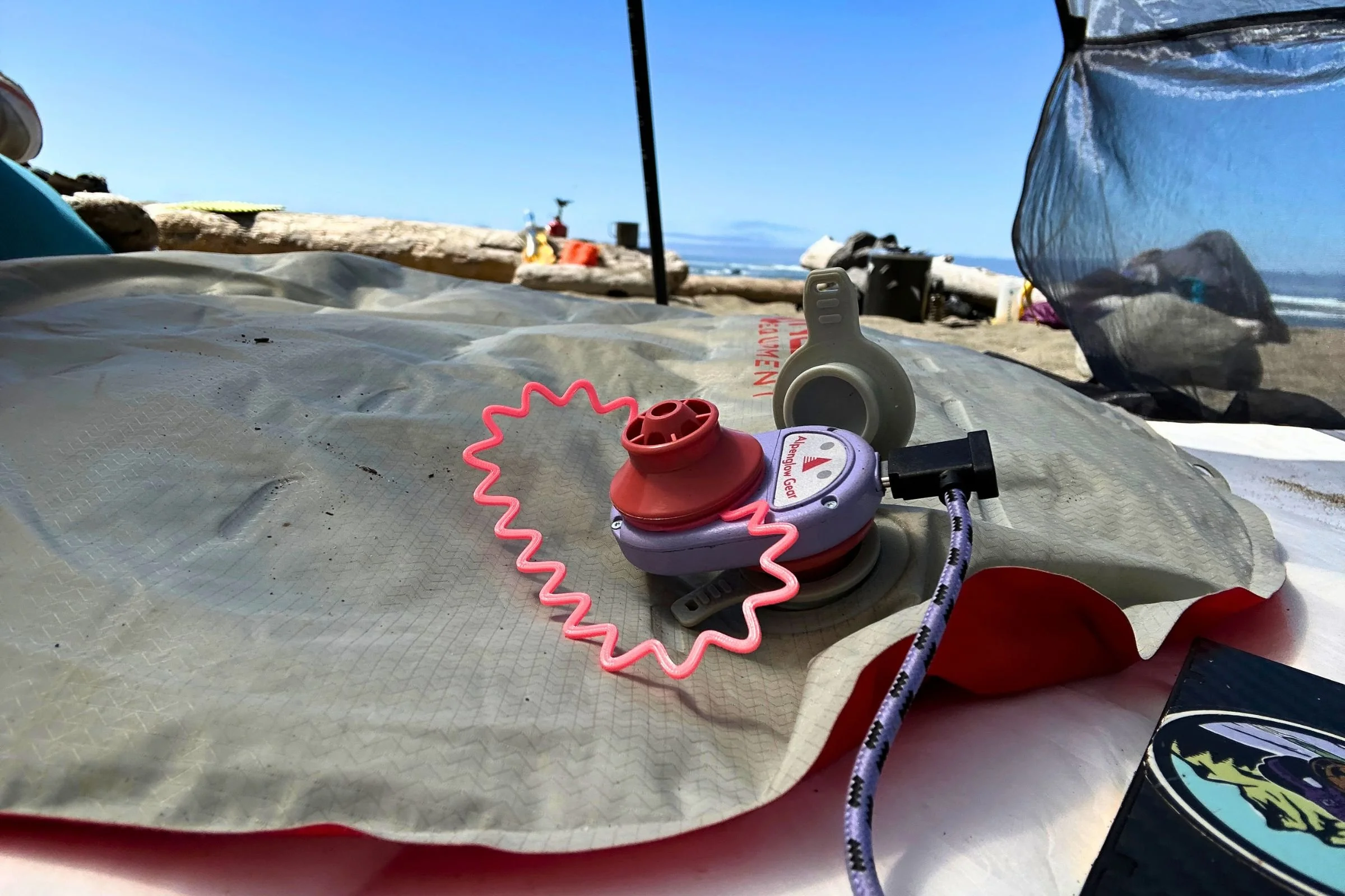 Using the Alpenglow Gear Alpenblow Lux inflator to inflate a sleeping pad at a coastal campsite