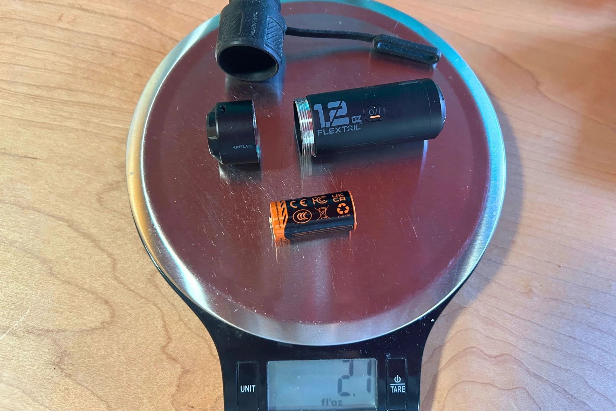   The FLEXTAIL ZERO PUMP and its accessories sit on a scale during testing. The compact pump weighs just 2.1 ounces with its battery and adapters.  