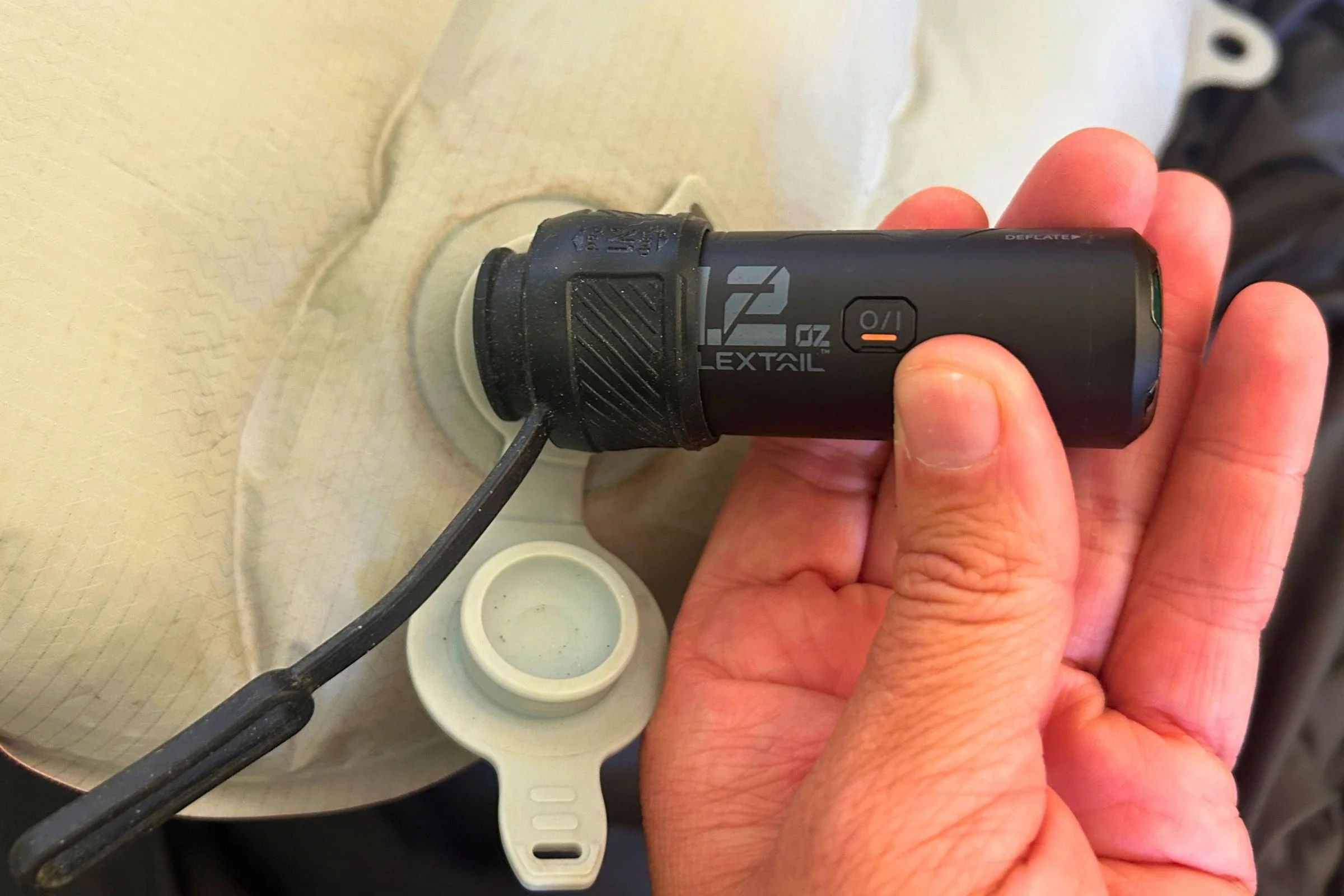   A tester holds the FLEXTAIL ZERO PUMP while it inflates a sleeping pad, demonstrating its small size.  