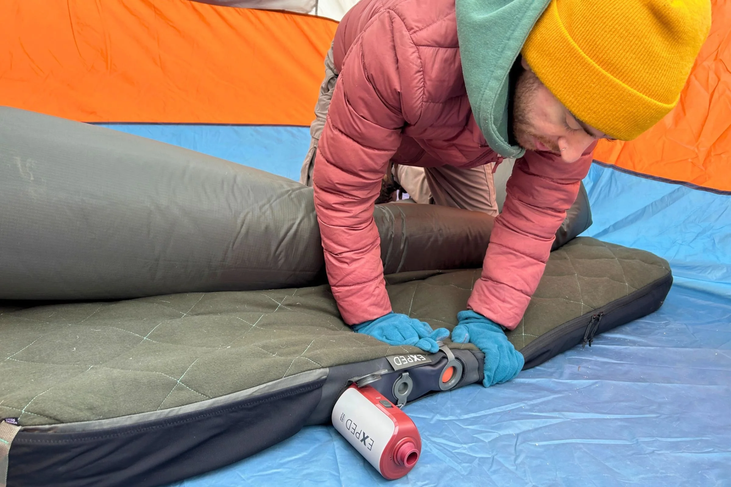   A tester uses the EXPED Mega Pump with a large camping mattress, where its more powerful motor makes quick work of high-volume car camping pads.  