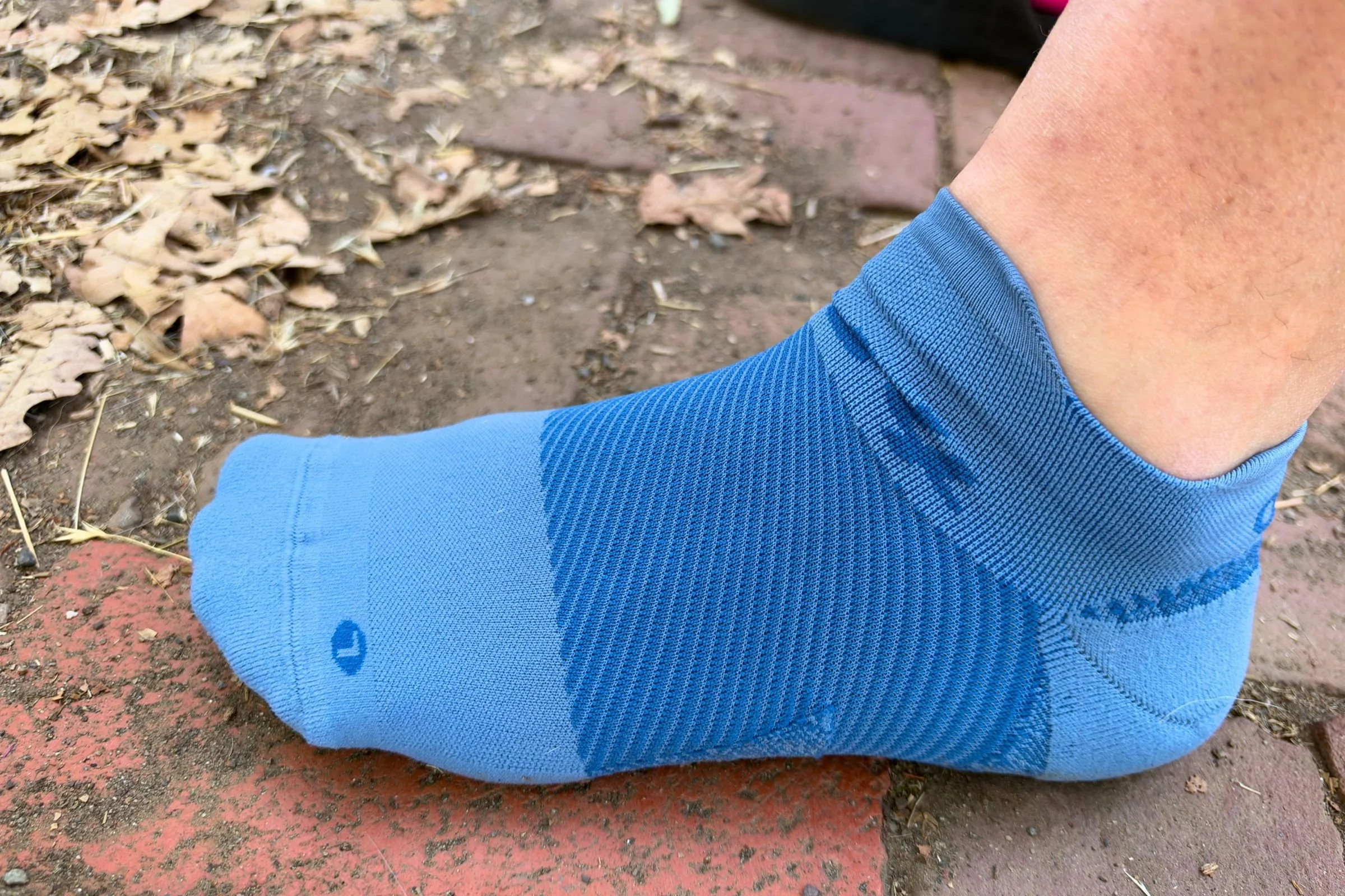   A close-up of the OS1st Plantar Fasciitis Quarter Crew Sock shows its ribbed compression zones across the midfoot and cushioned heel, which help keep the sock securely in place and reduce slipping during long runs.  