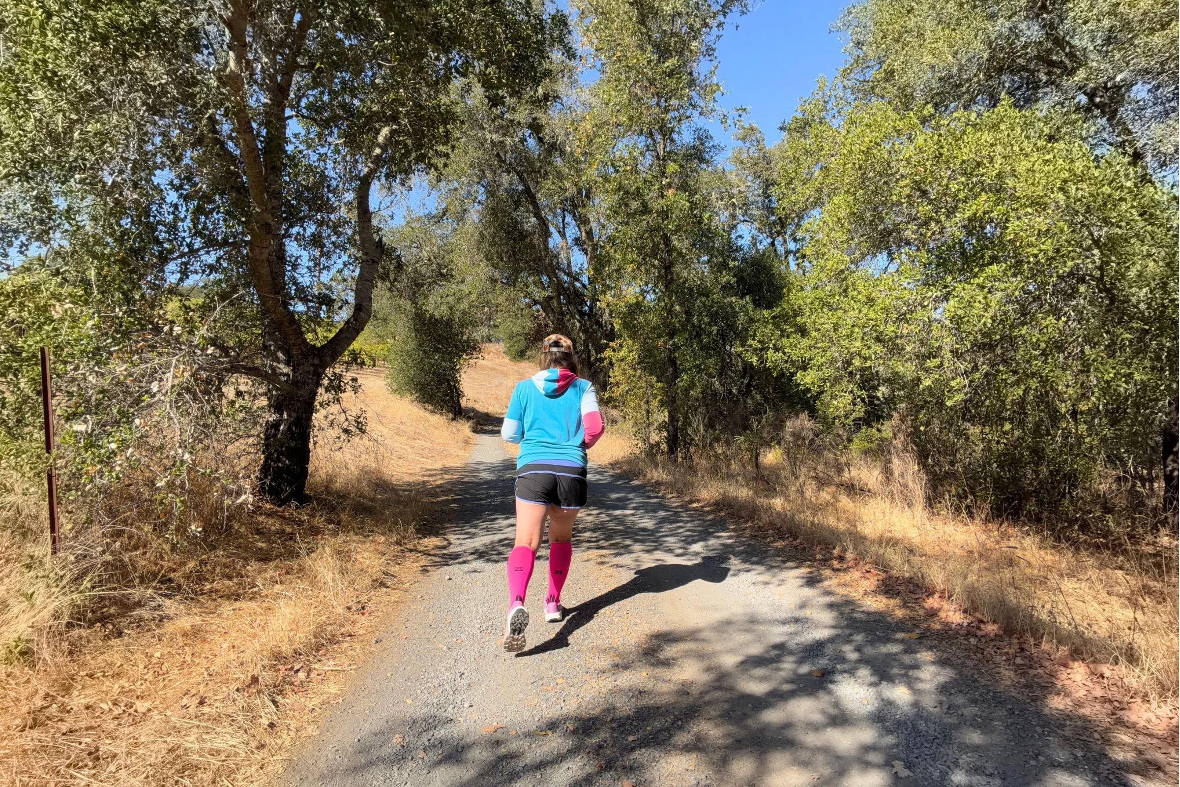   A runner heads down a wooded trail wearing the Zensah Tech+ Graduated Compression Socks, which held up well during testing on hilly, rocky, and dusty routes.  