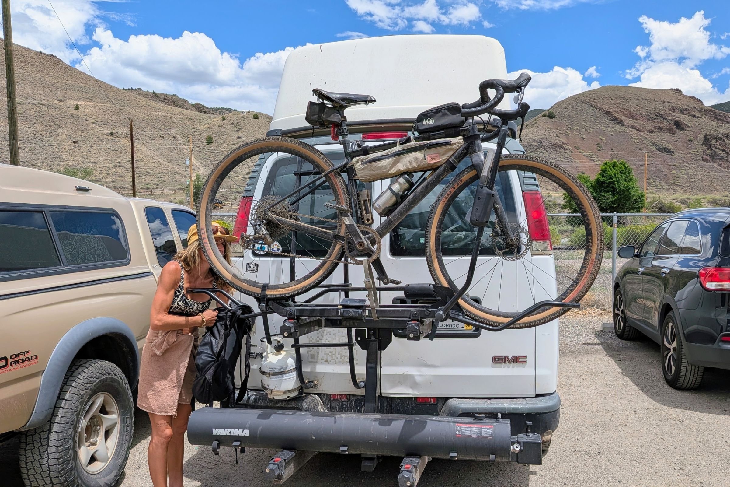Woman loading a bicycle onto a van.