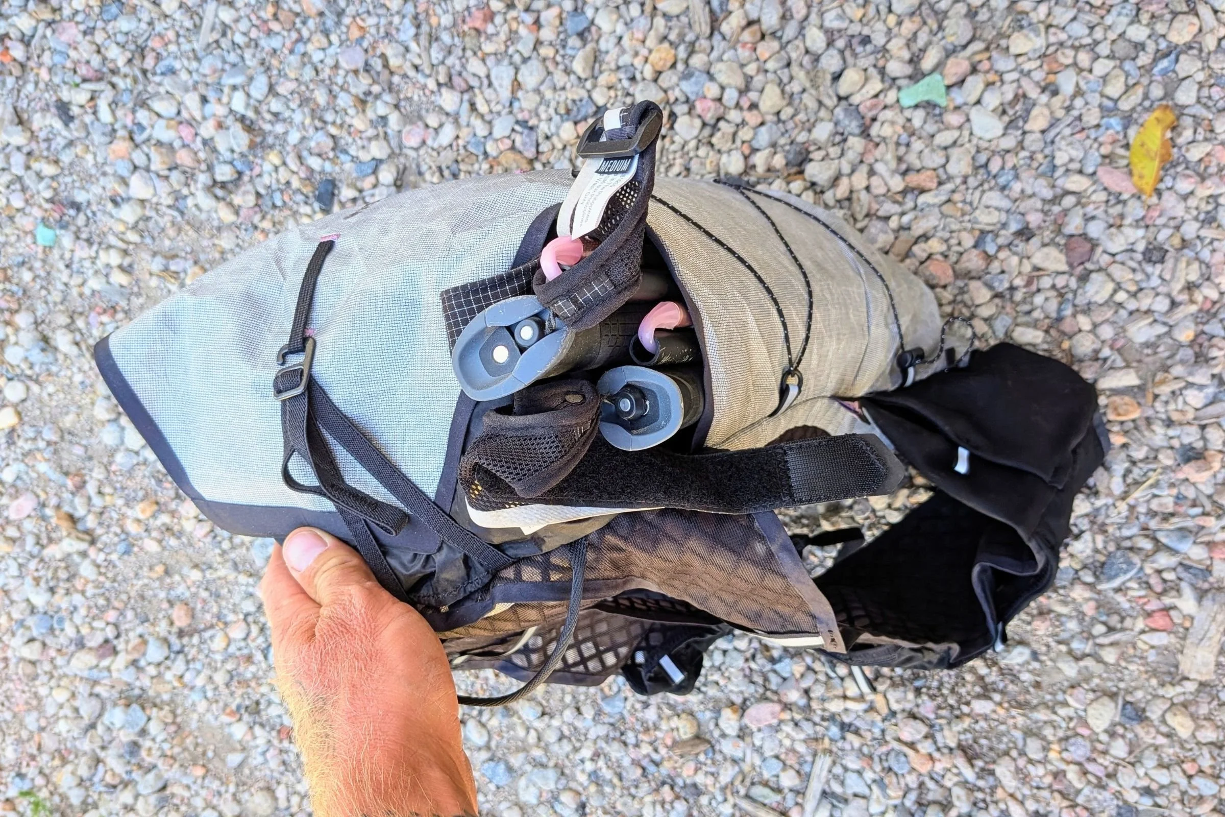 Top view of folded trekking poles stored in a side pocket of the Black Diamond Distance 15 Backpack