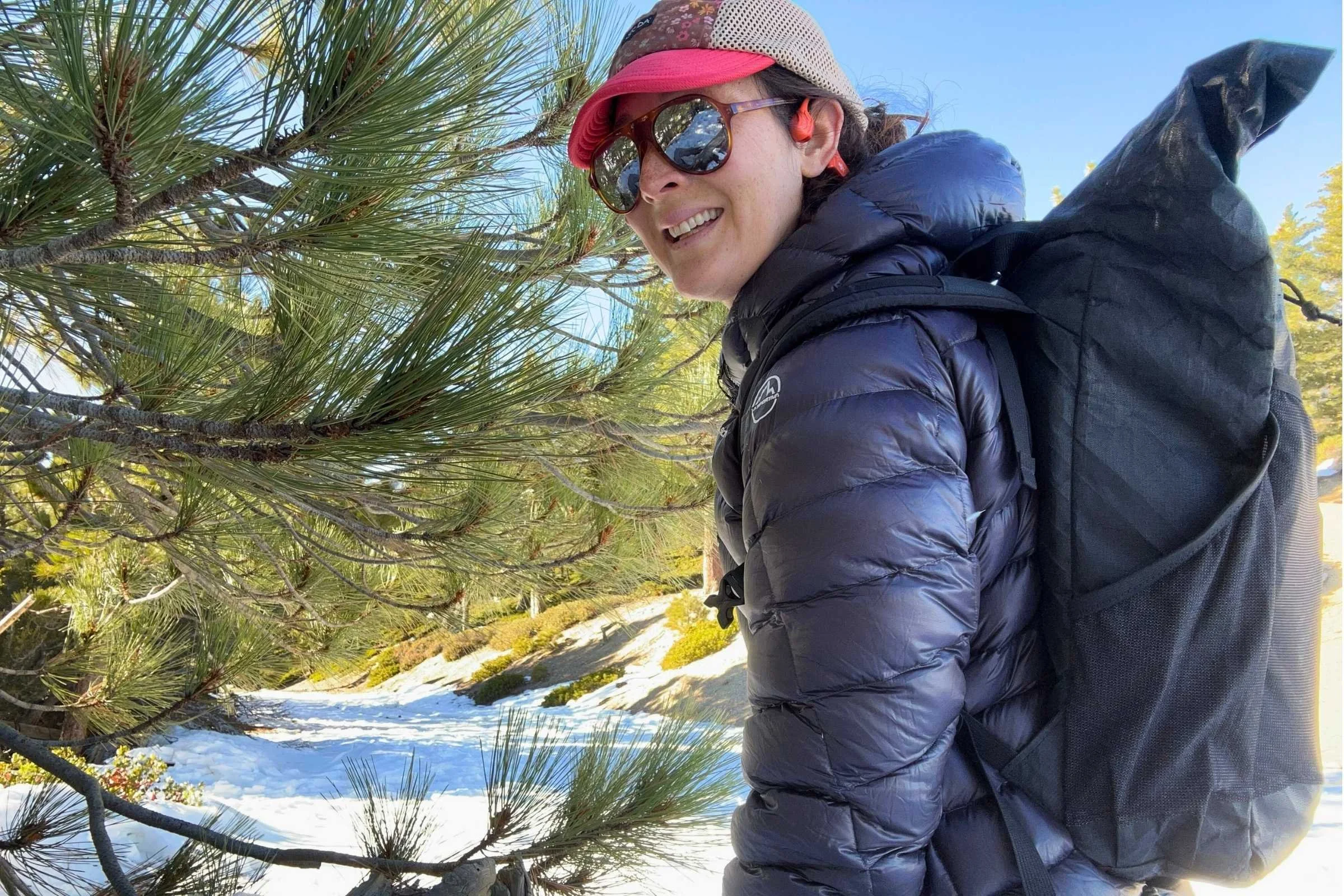 woman hikes on snowy trail in the La Sportiva Lumina 200 down jacket