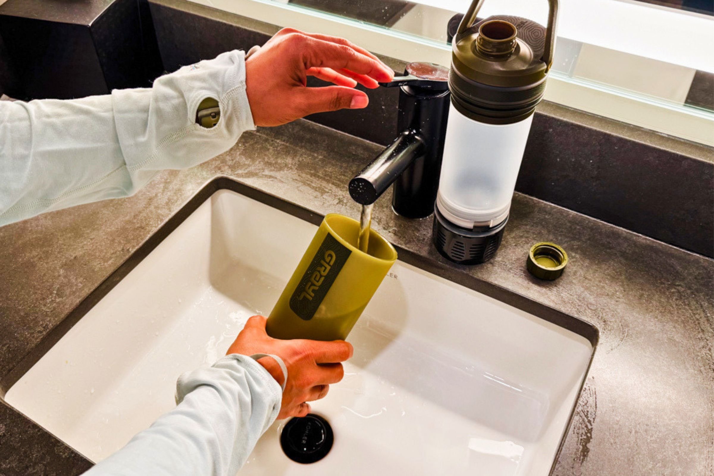 Water is being poured from a faucet into Grayl UltraPress Filter and Purifier Bottle