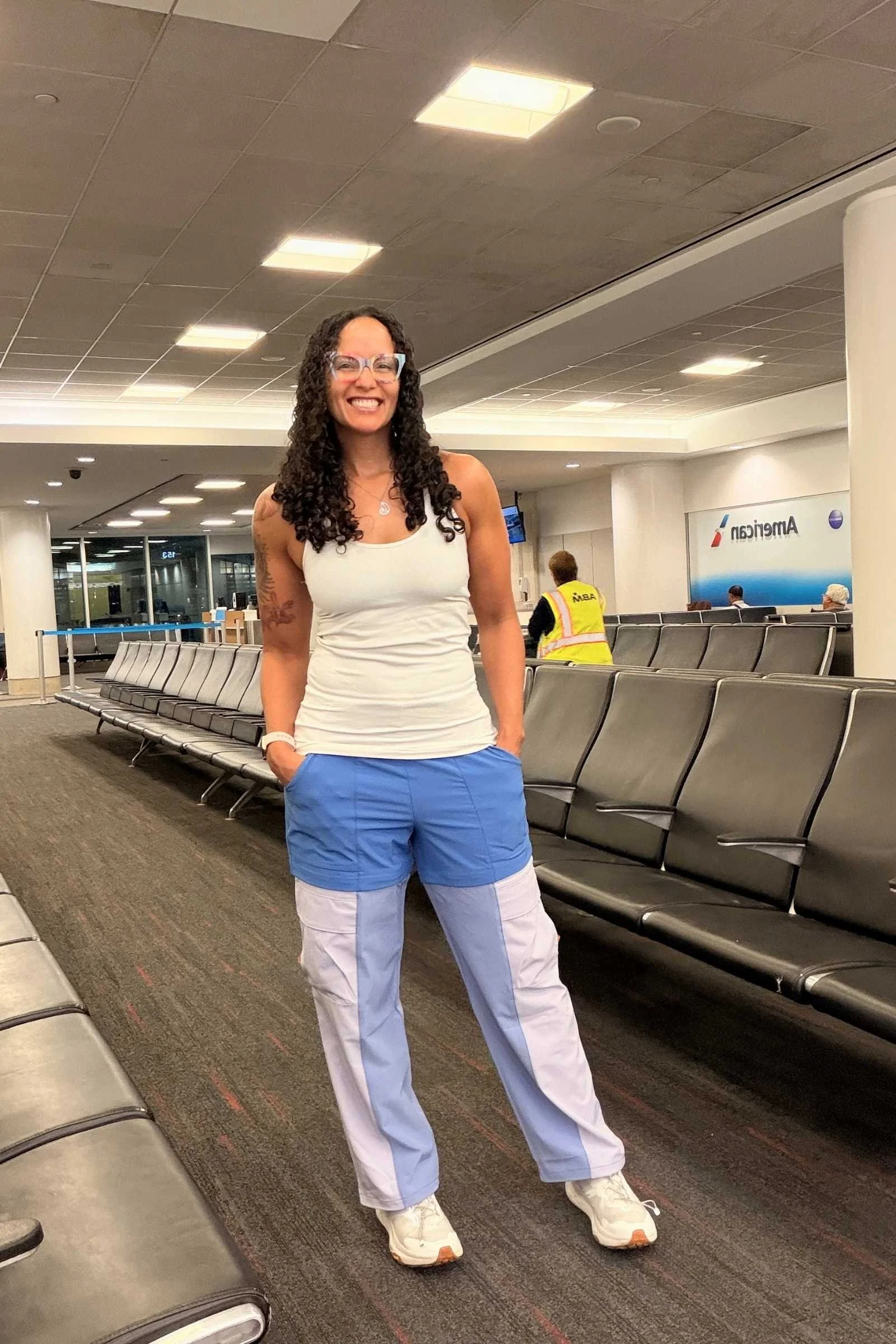 Woman wearing Cotopaxi Losdos Zip Off travel pants in blue and cream in an airport
