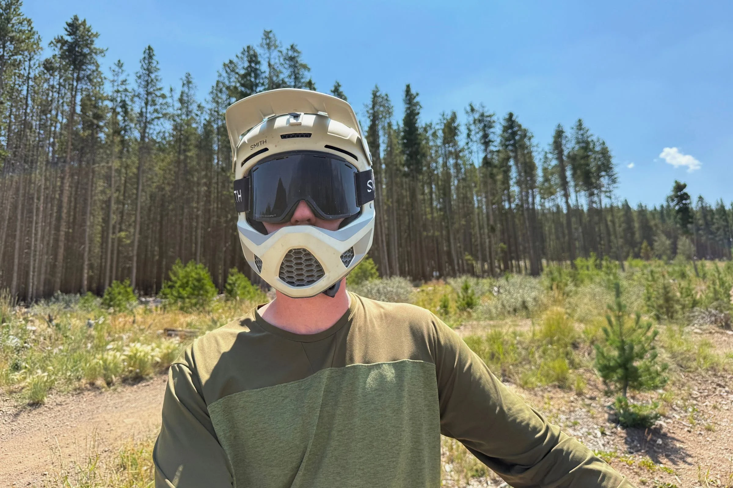 A man wearing a Smith Hardline helmet with goggles in a wooded setting.