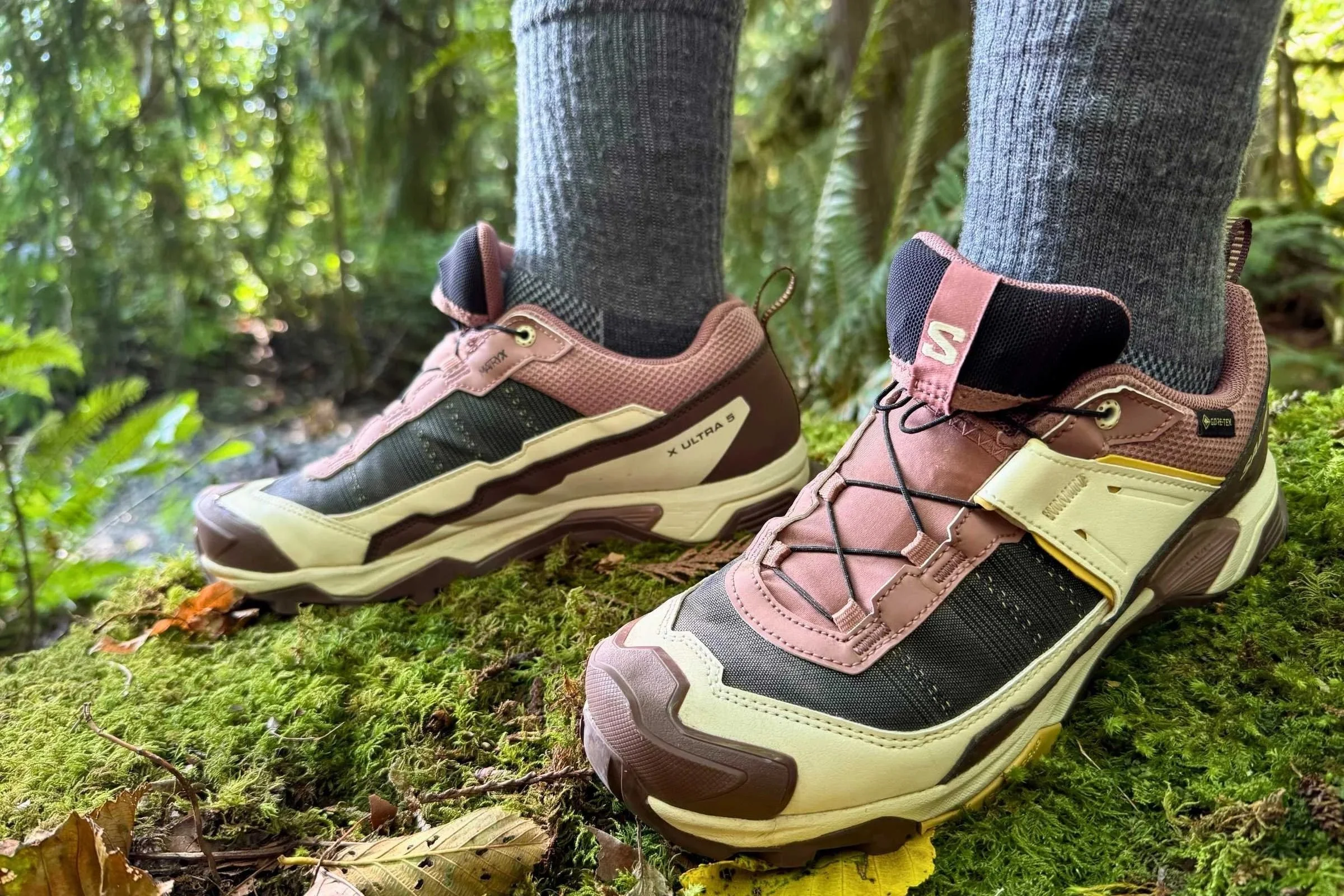 Person wearing the Salomon X Ultra 5 GTX hiking shoes standing on a mossy log in a forest