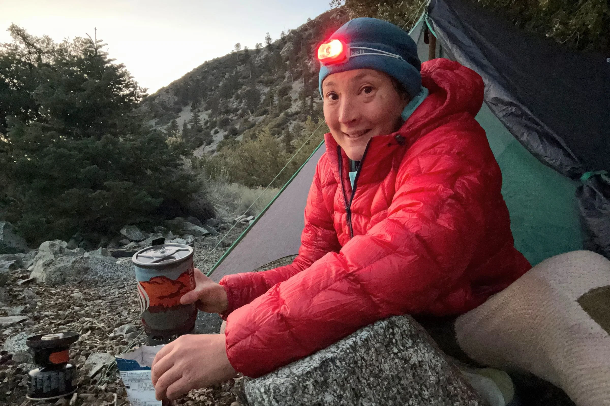 The author testing the Petzl Swift LT headlamp while sitting inside her backpacking shelter.
