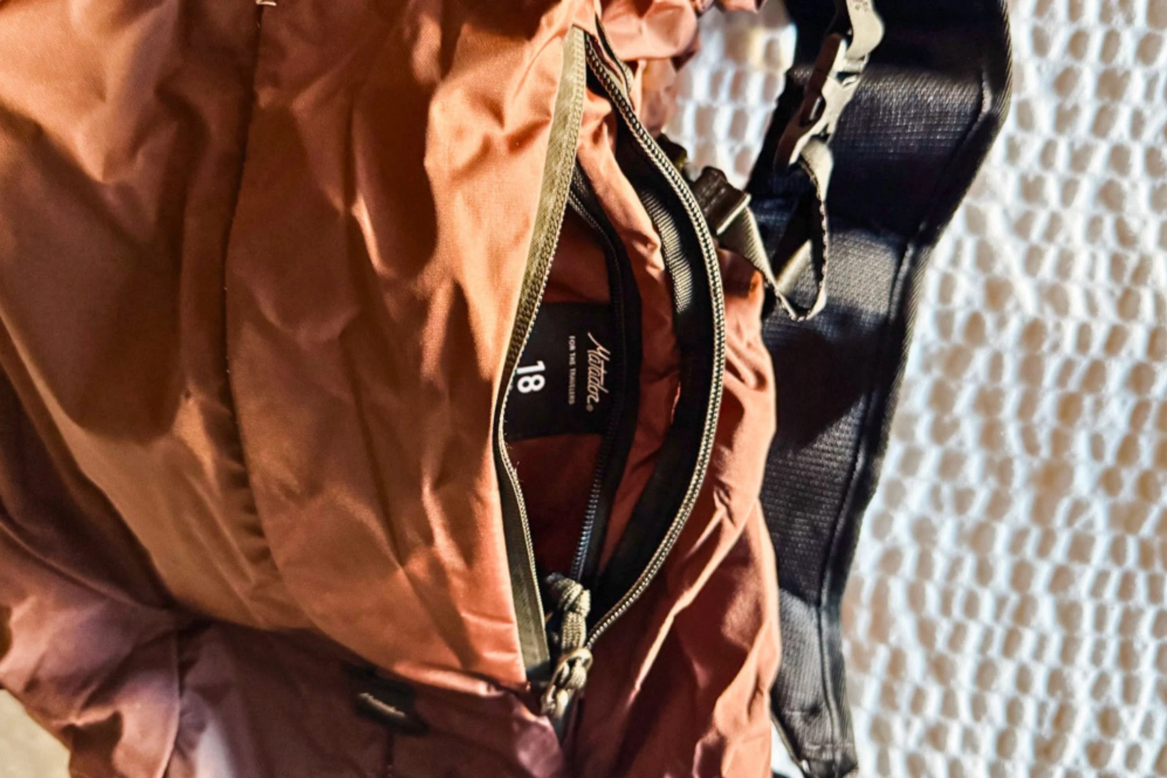 The Matador 18L Waterproof Packable Backpack with its front pocket open, showing the labeled packing pocket inside.