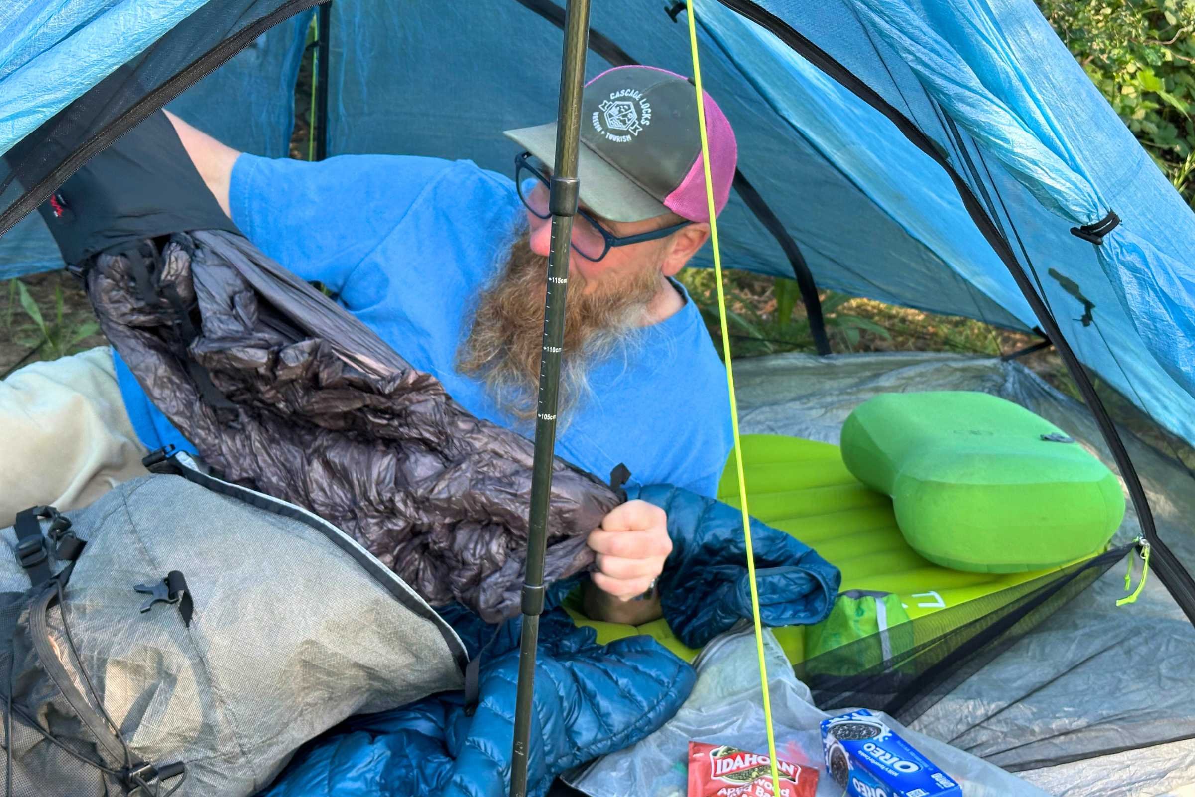 Tester setting up camp inside their shelter. They are unpacking their quilt while lounging on the EXPD Ultra 6.5R Mummy sleeping pad