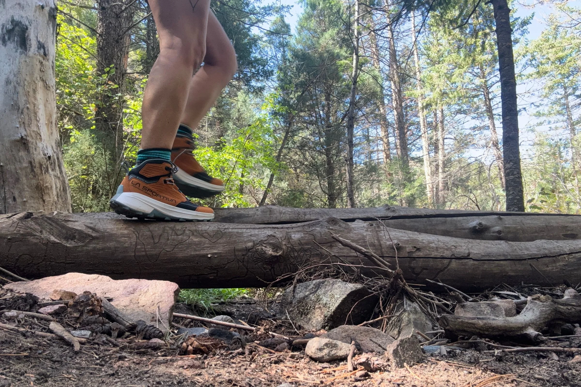 Woman wearing La Sportiva Prodigio Hike LT GTX Hiking Boots, standing on a log in a forest.