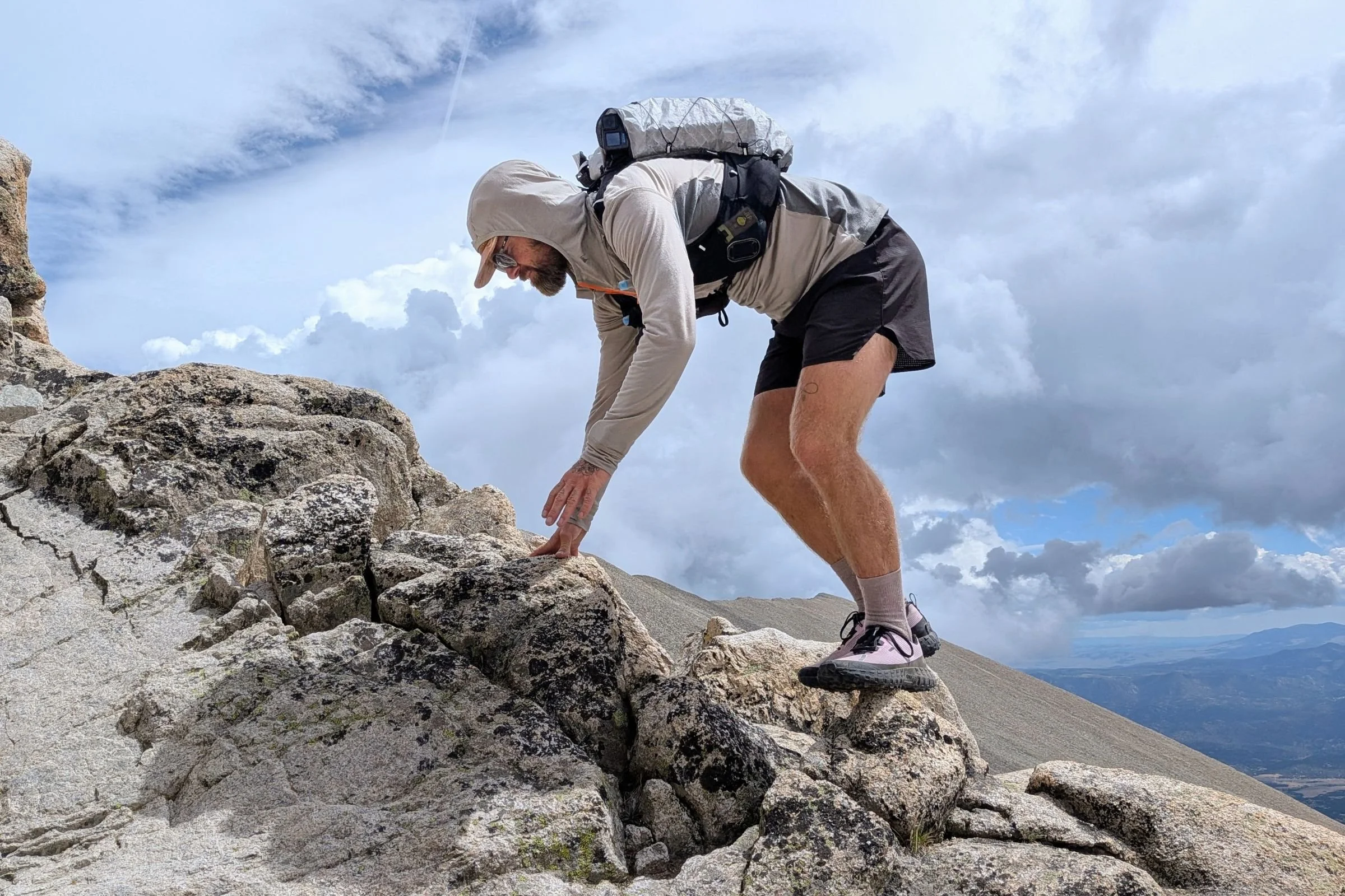 A man climbs a mountain wearing the Black Diamond Distance 15 Backpack.