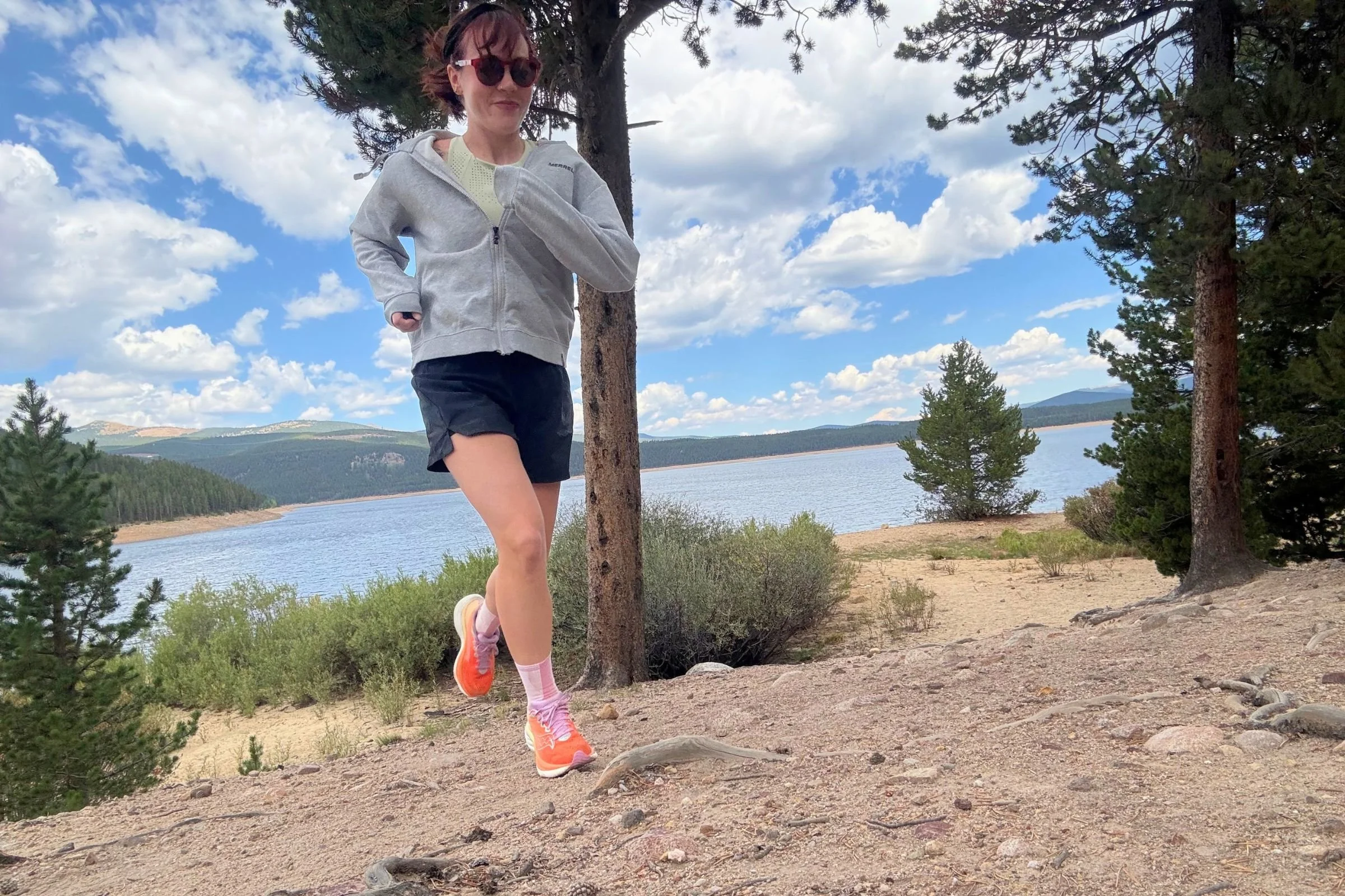 The author Becca Downs wearing the Saucony Ride 19 on a dirt trail next to a lake.