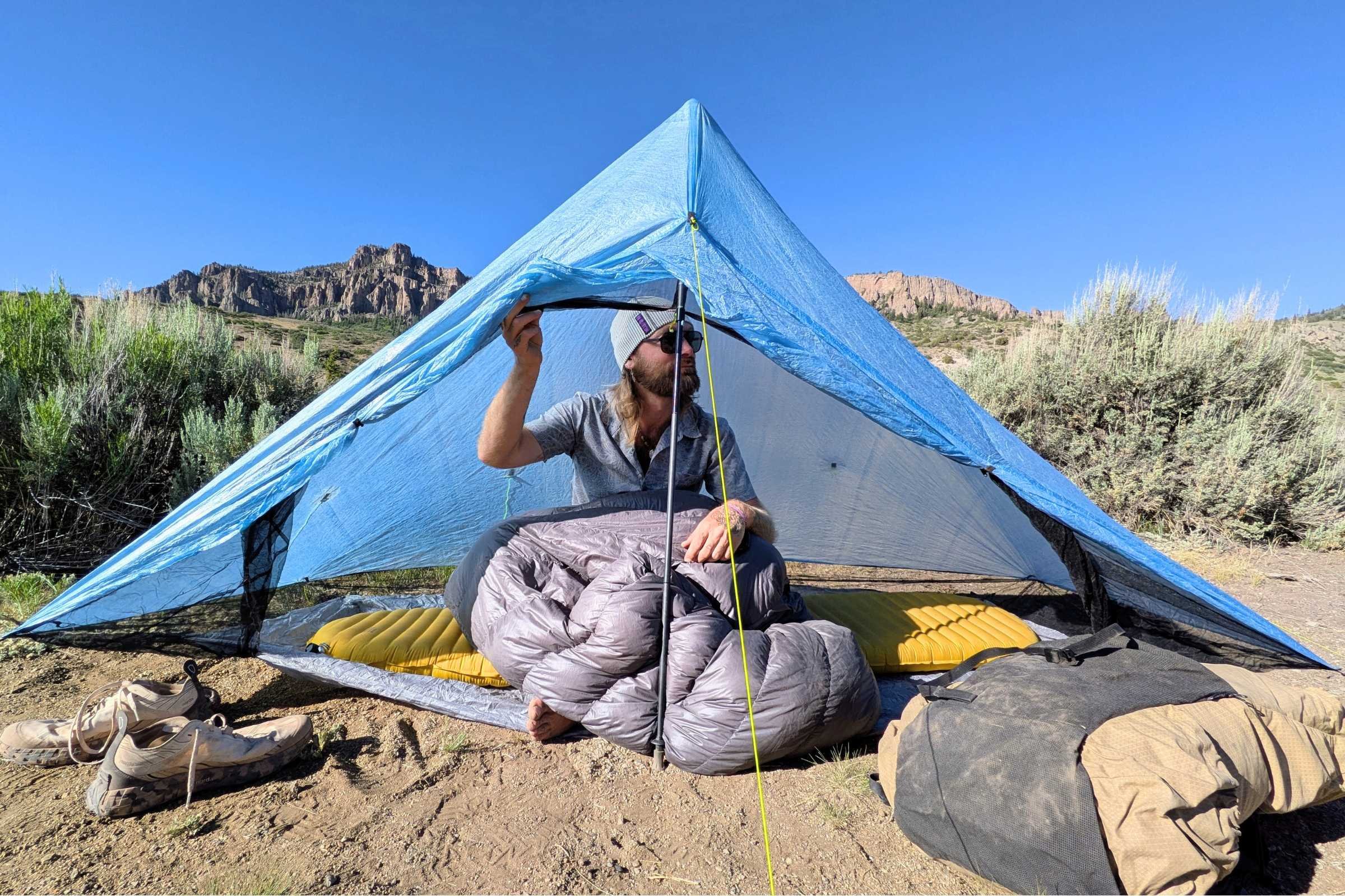 Man sitting inside a Zpacks Hexamid Ultralight Tent with a sleeping bag.