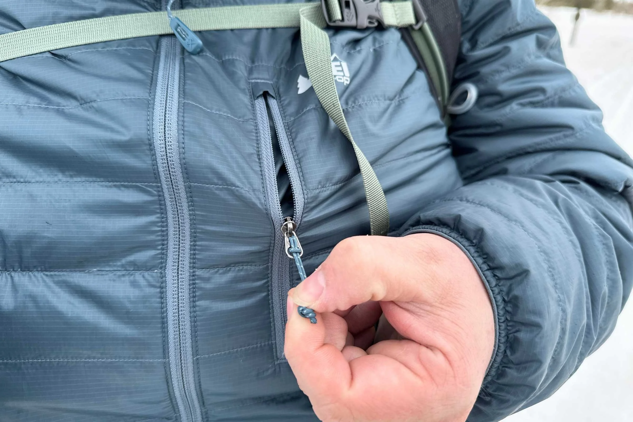 The chest pocket unzipping on the REI Microtrek Hoodie in men’s.