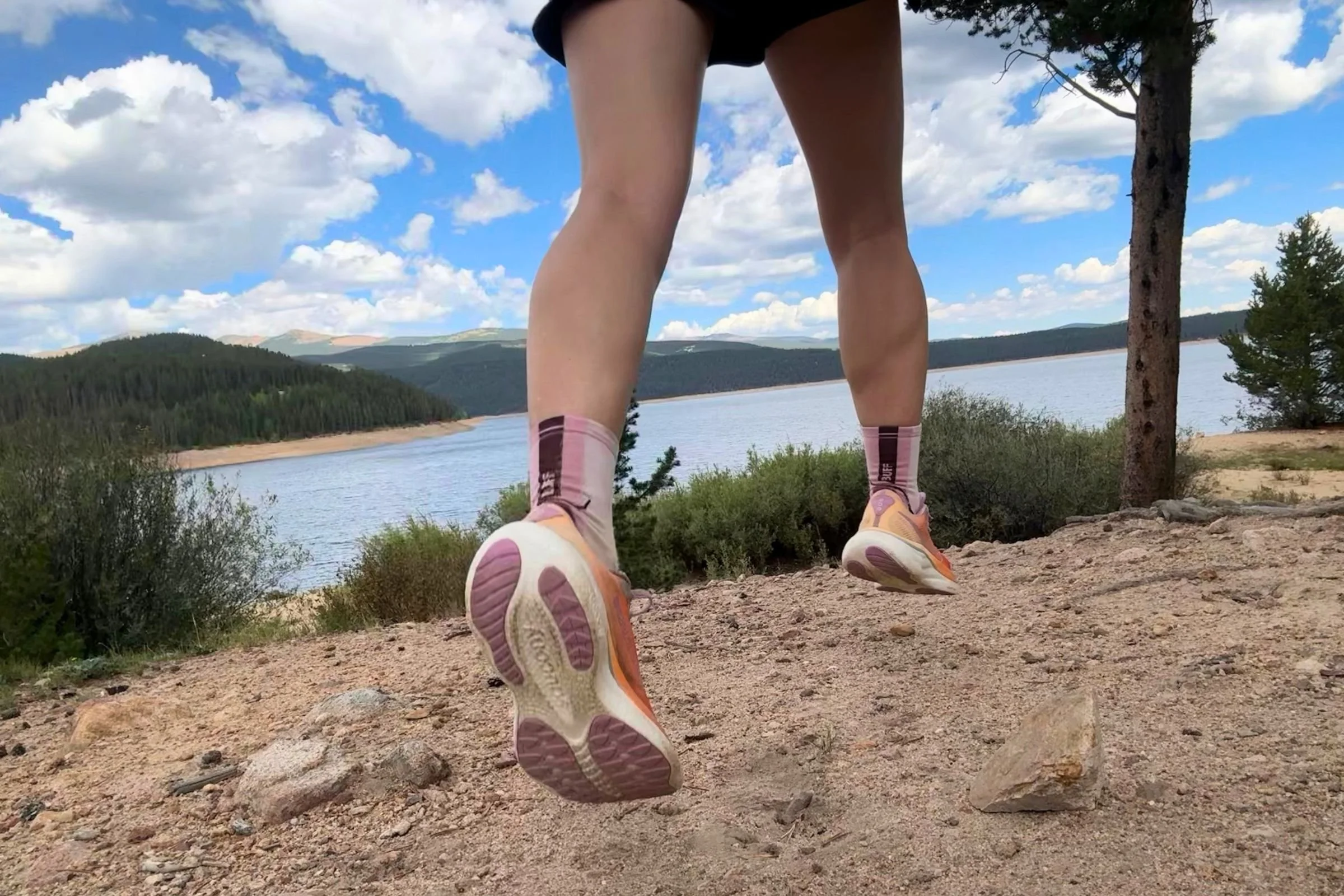 Person wearing the Saucony Ride 19 on a gravel trail with a lake in the background.