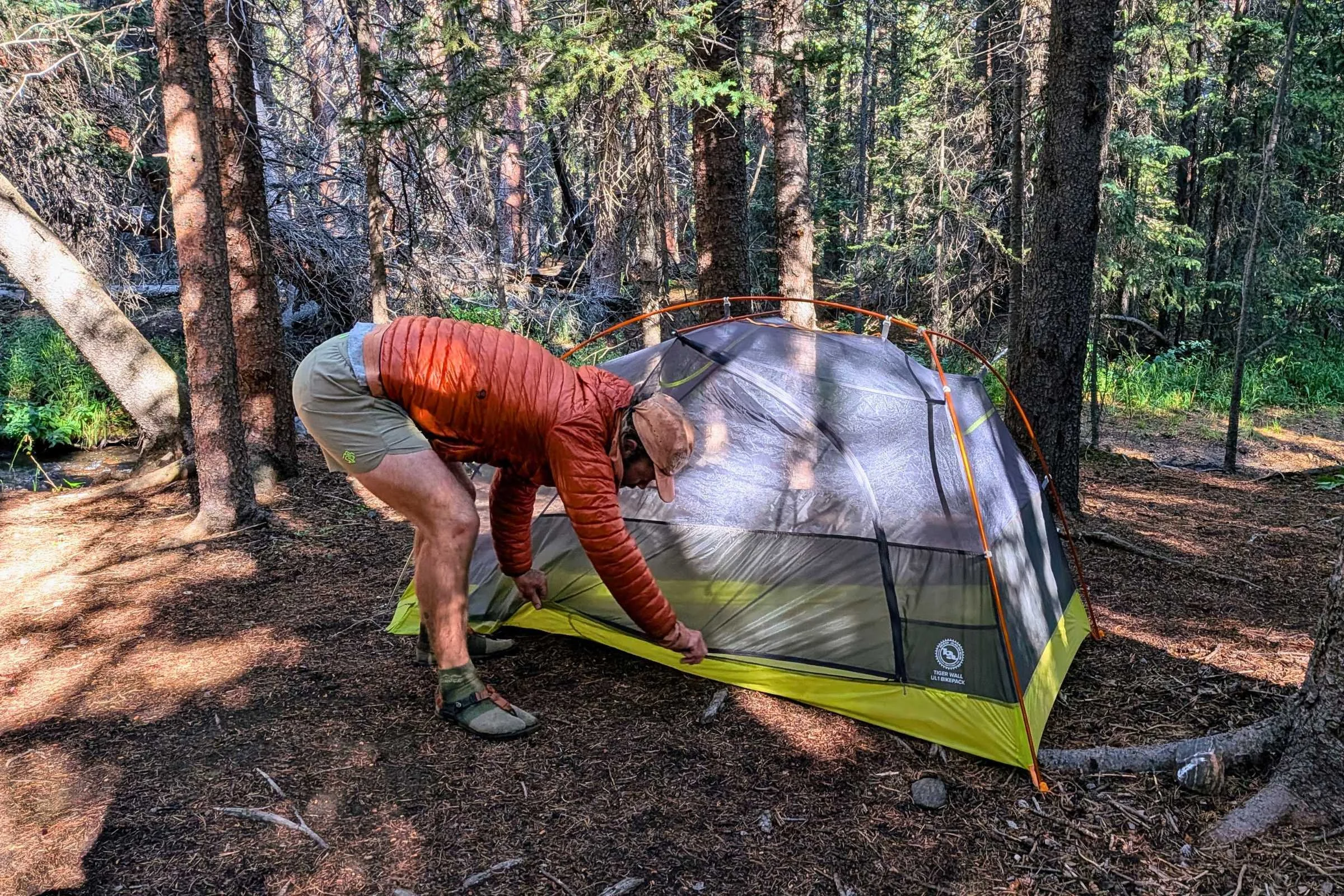 A man setting up a backpacking tent while wearing rabbit FKT Shorts