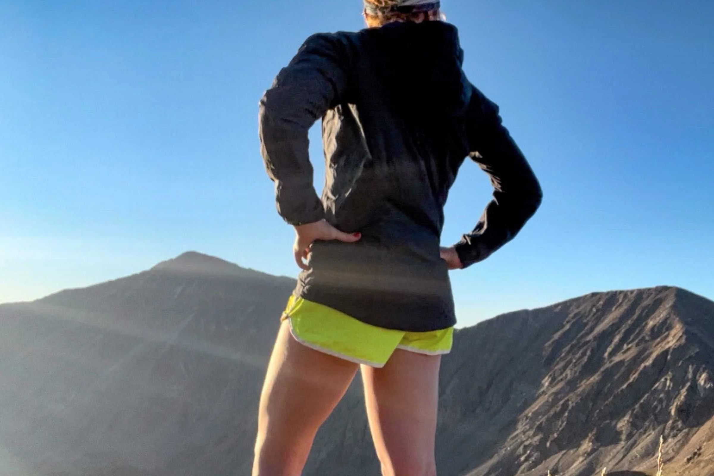Runner wearing a black Patagonia Houdini running jacket overlooks a high alpine ridge