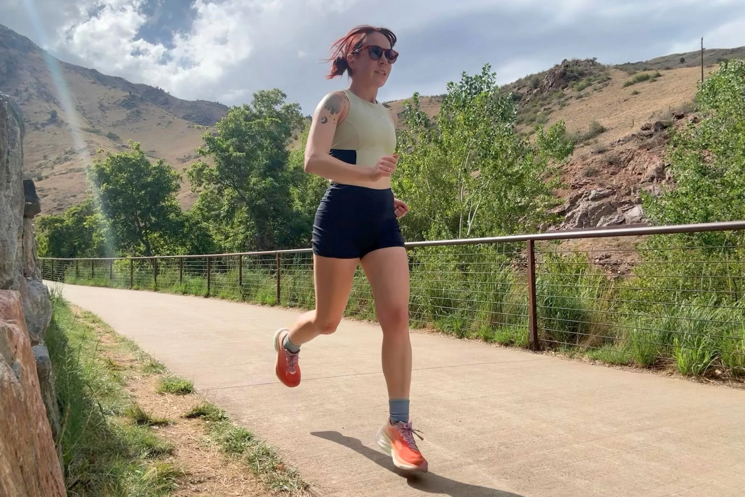 Saucony Ride 19 Road Running Shoes worn by a woman running along a paved mountain trail.