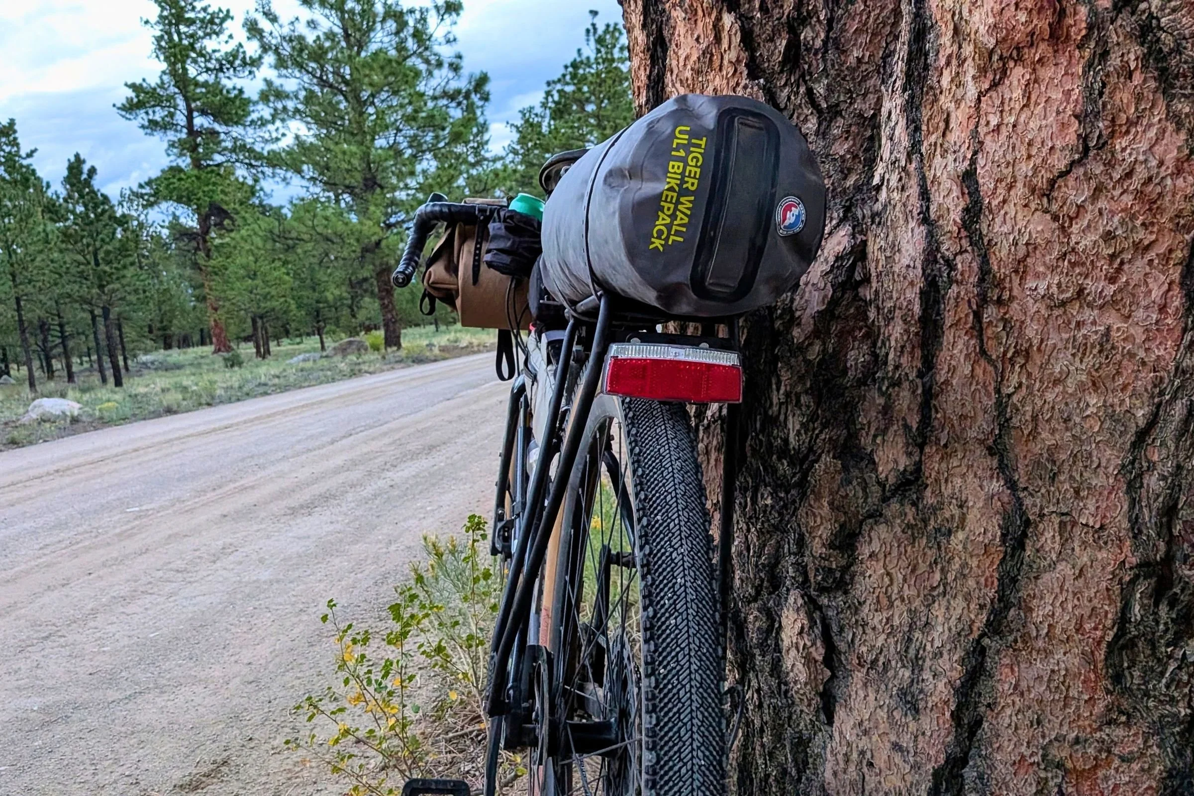 The Big Agnes Tiger Wall UL1 Bikepack Tent in its stuff sack strapped to a rear bike rack (view from behind the bike).